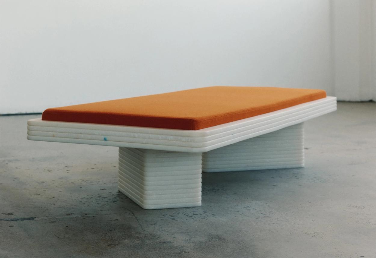 White frame table with large orange cushion atop