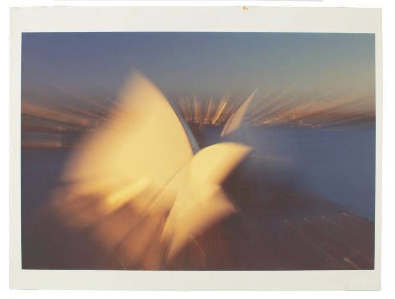 A blurred aerial view photograph of the Sydney Opera House.