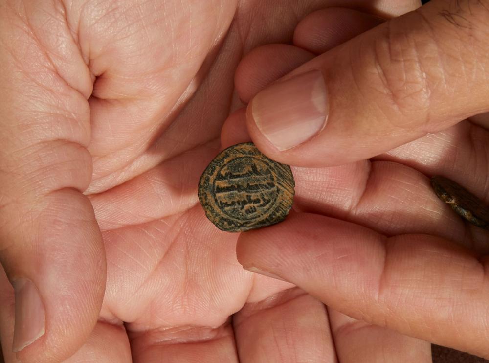 Photograph of ancient coin in palm of hand