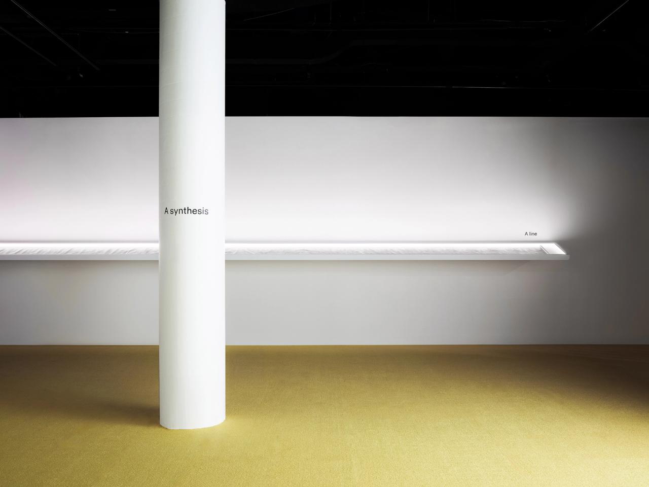 White pillar in front a long display shelf, with yellow flooring