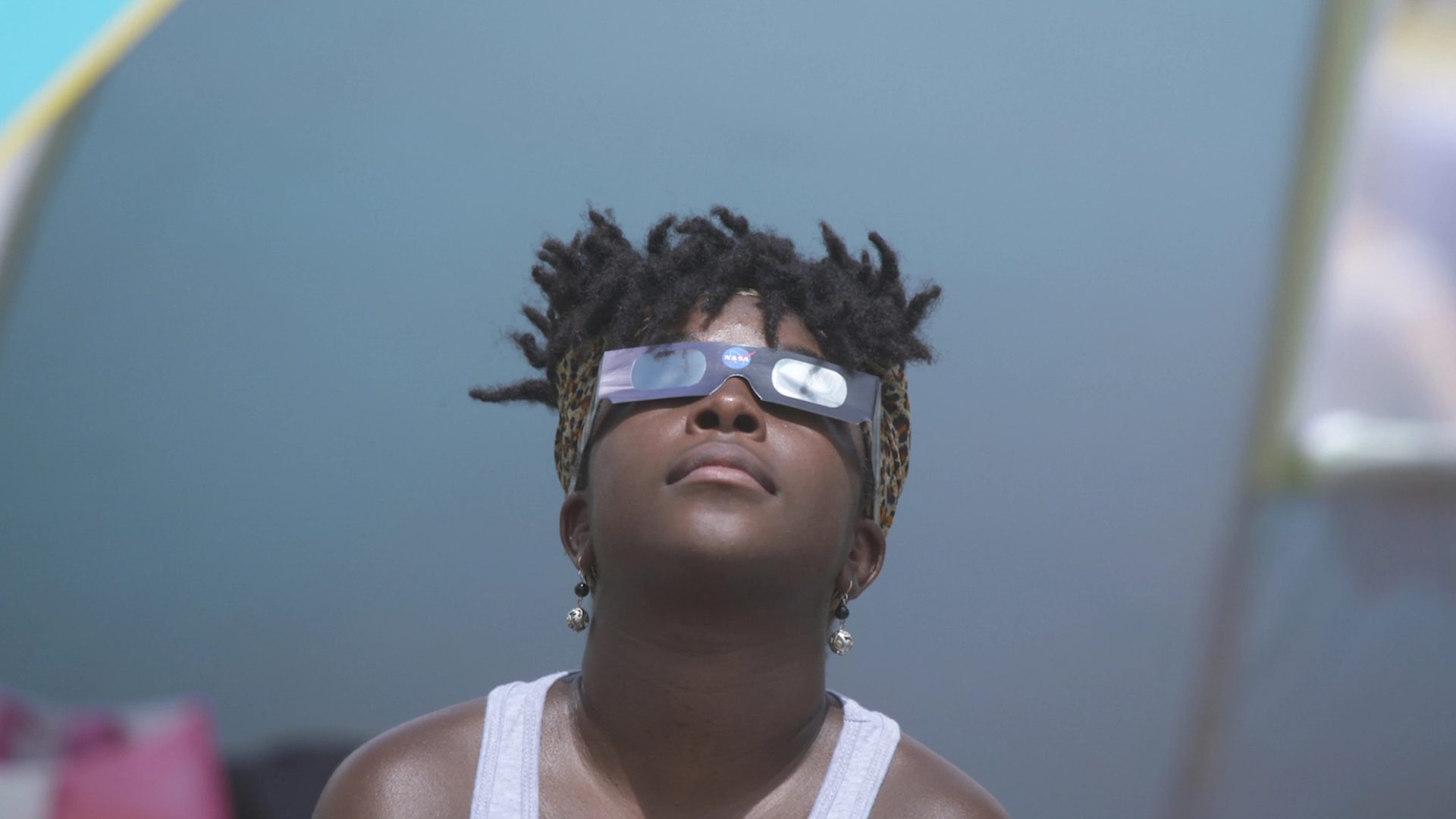 Close-up of a figure looking upwards wearing cardboard glasses.