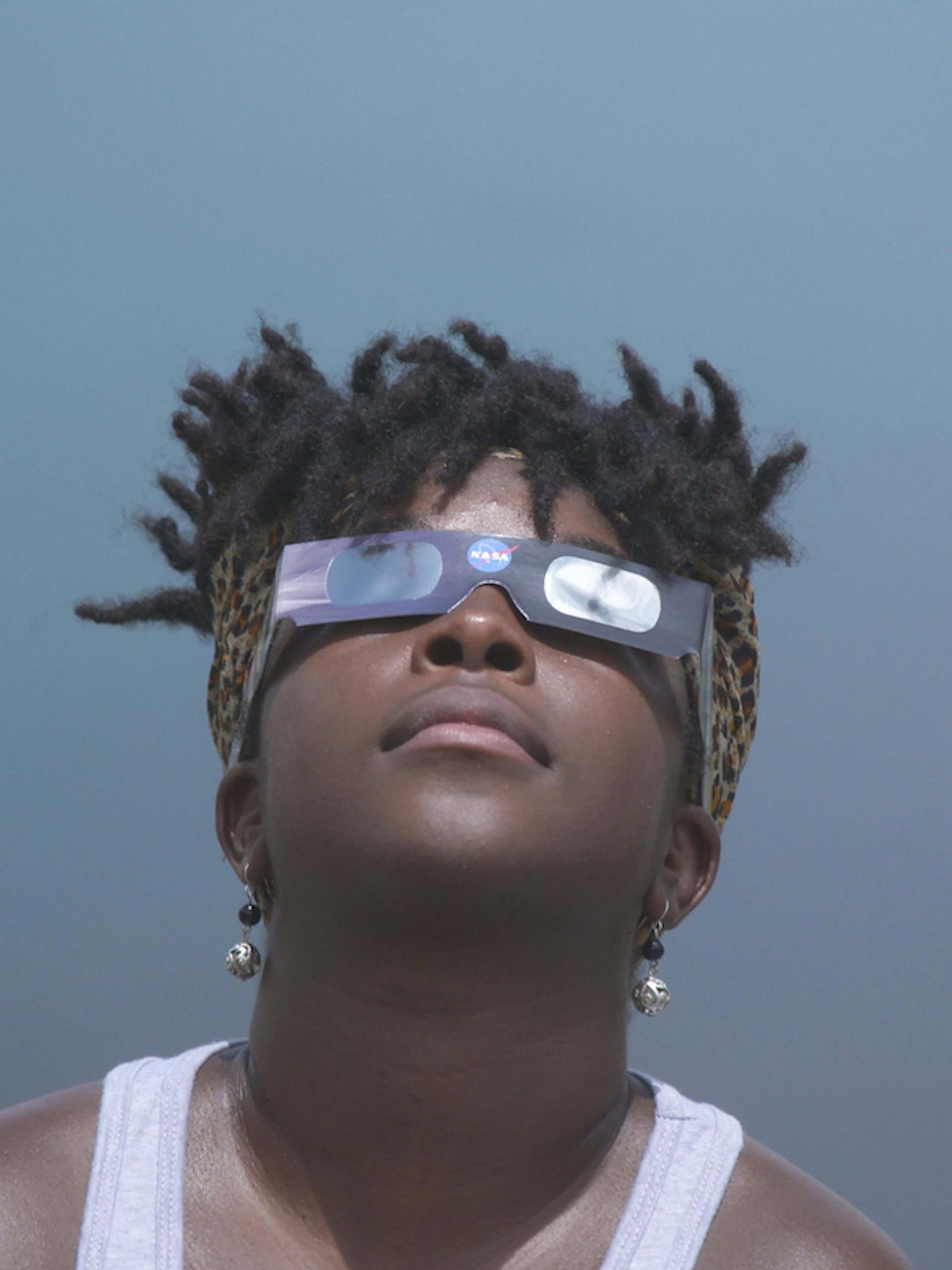 Close-up of a figure looking upwards wearing cardboard glasses.
