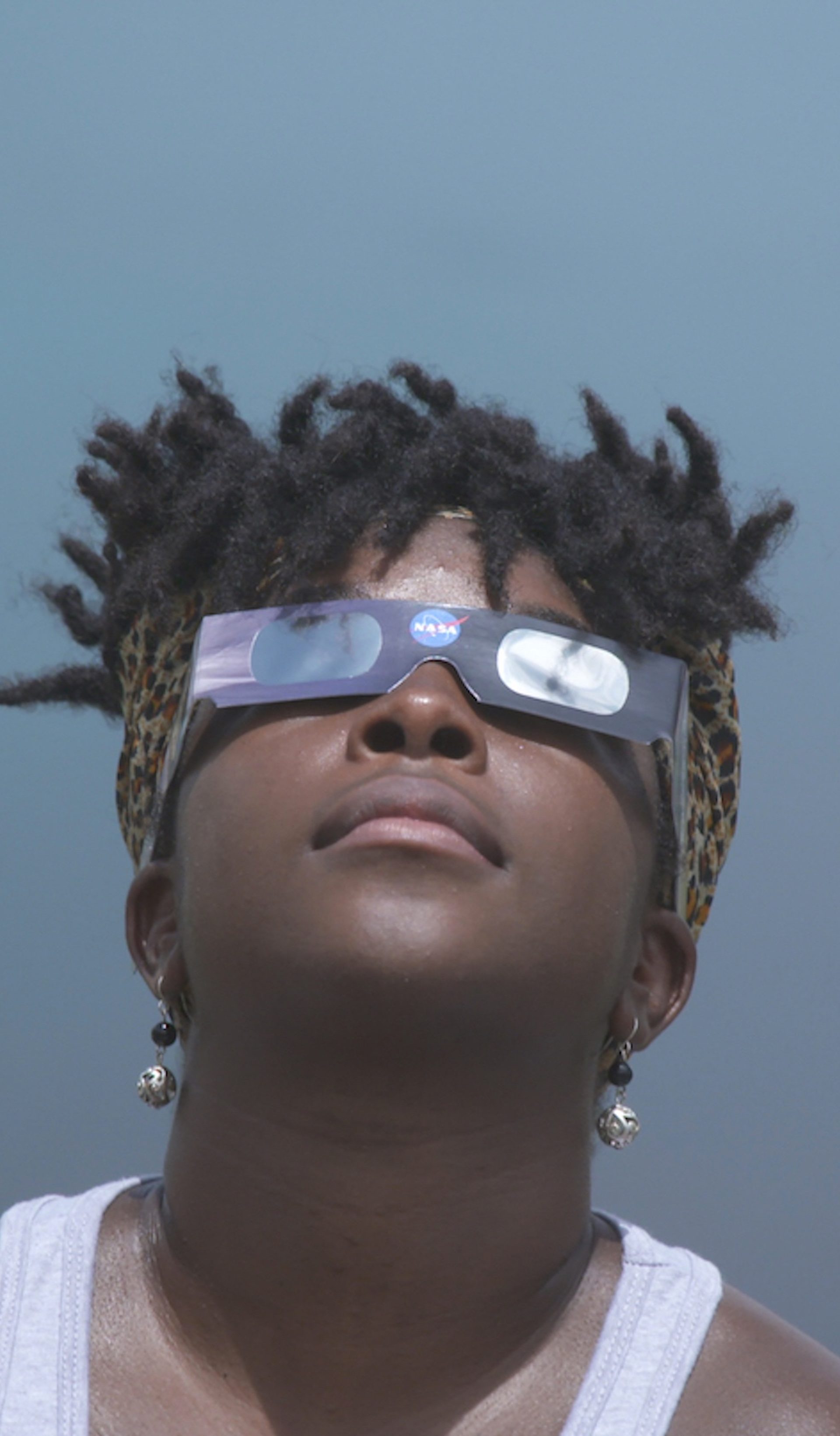 Close-up of a figure looking upwards wearing cardboard glasses.