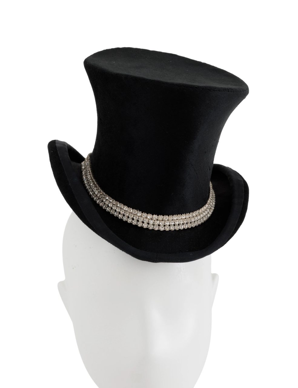 Top hat of black beaver skin, edged around the brim with ribbed black braid, made by Rosie Boylan. All around the brim runs 3 lines of diamantes in silver settings. The hat is lined with white polyester and there are small tabs of pink woven horsehair protruding from under the lining.