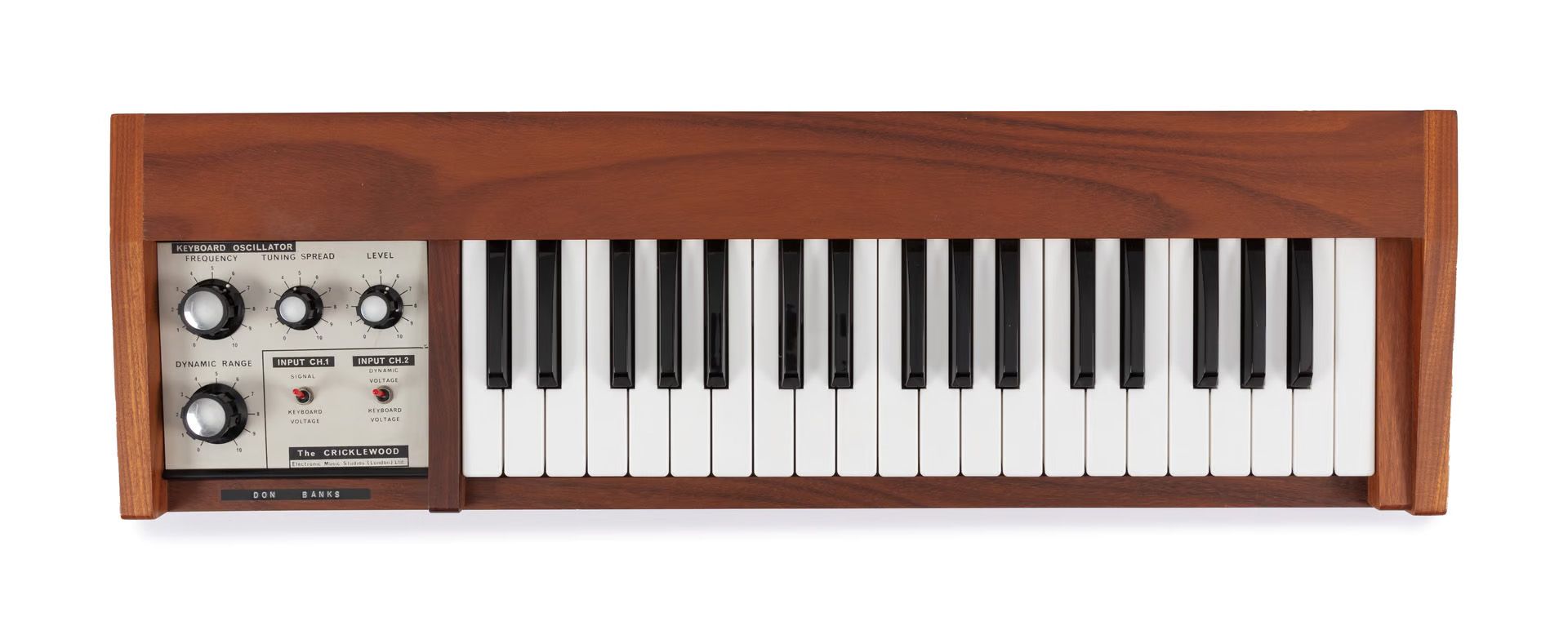 Wooden keyboard with synthesiser panel with four knobs on the left.