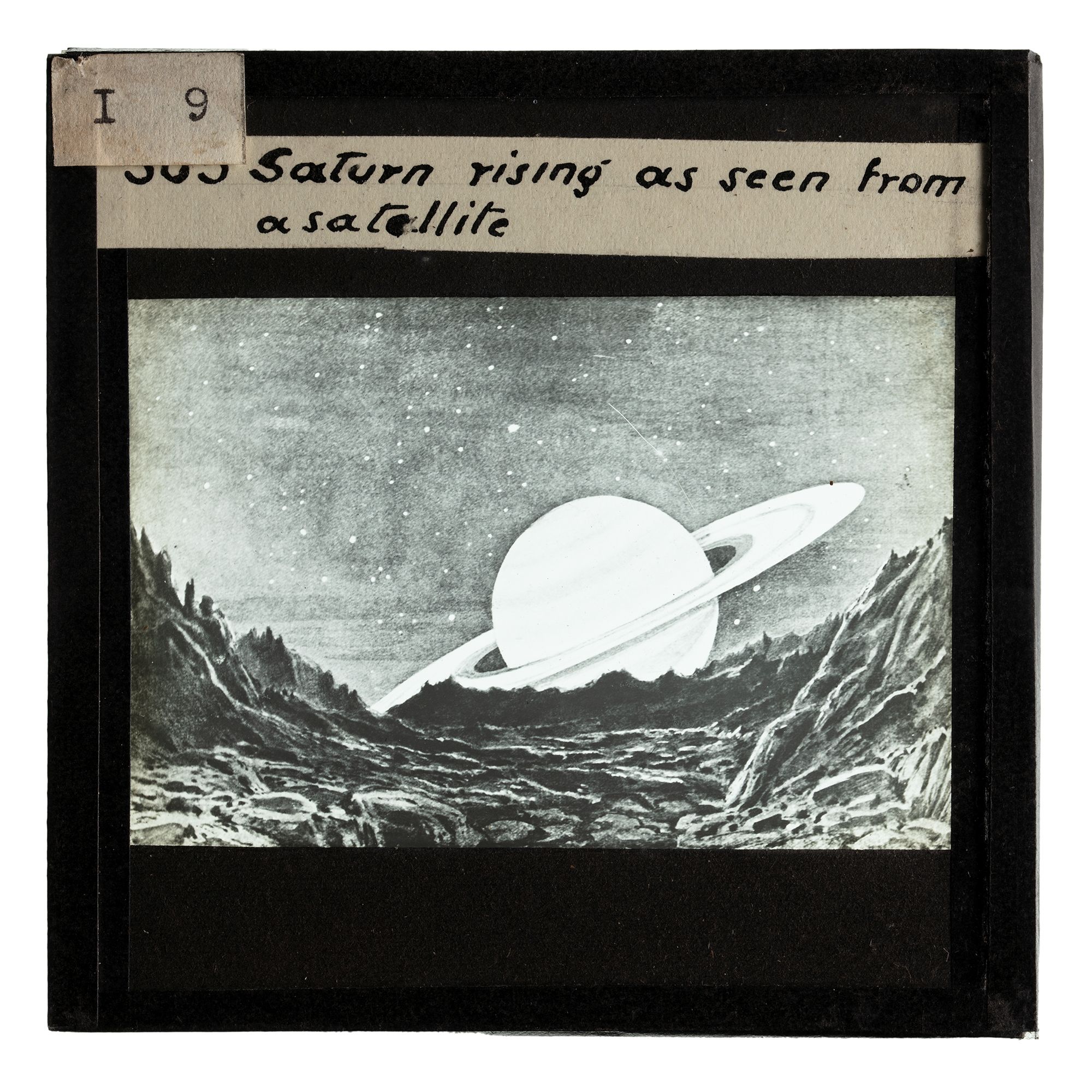 A drawing of the planet Saturn is depicted in black and white on a glass slide photograph