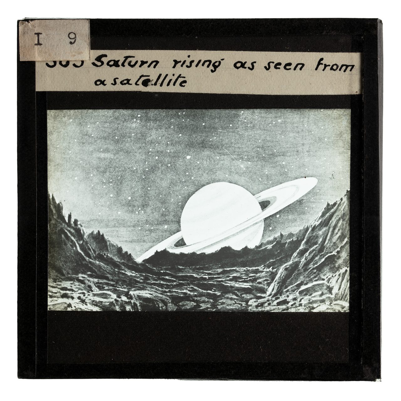 A drawing of the planet Saturn is depicted in black and white on a glass slide photograph