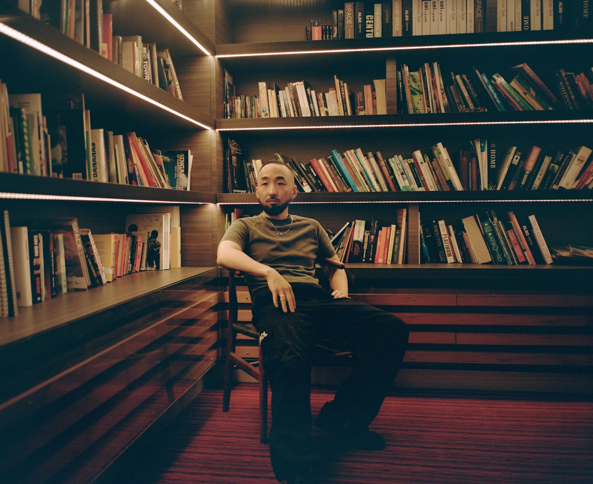 Figure sits in dimly lit library room.