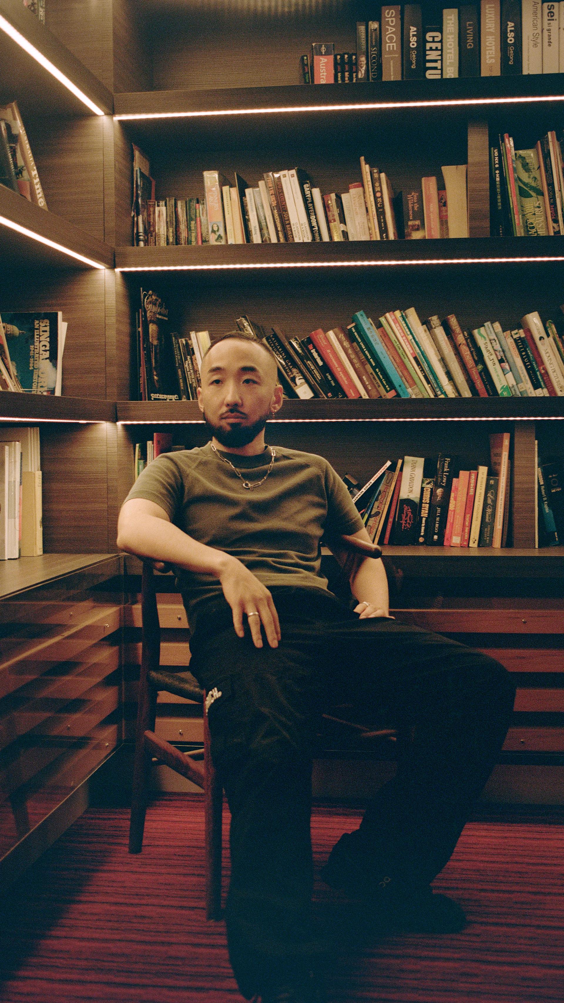 Figure sits in dimly lit library room.