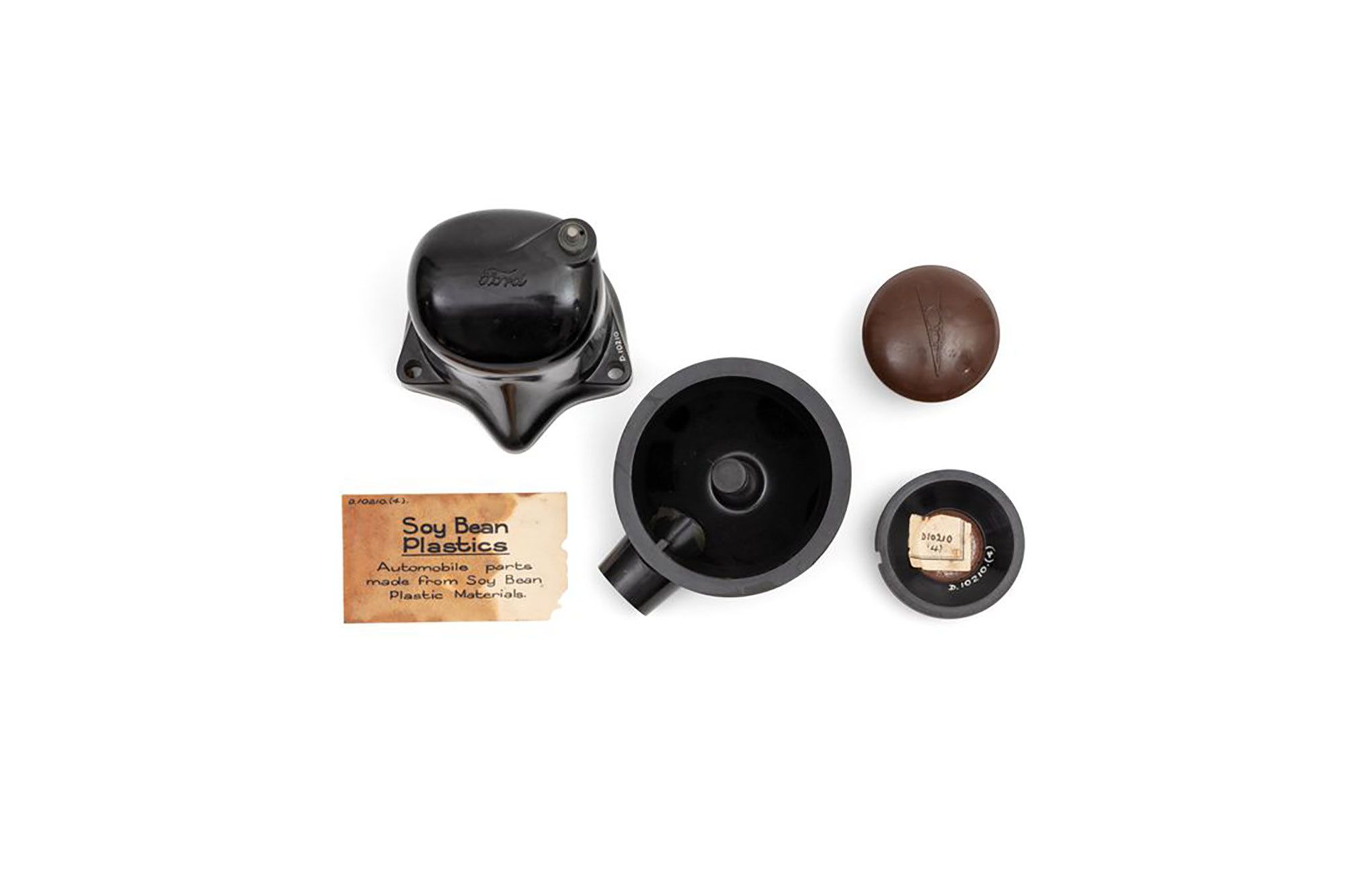 Specimens (4) of black automobile parts and museum label, 'Soy bean plastics, Automobile Parts'