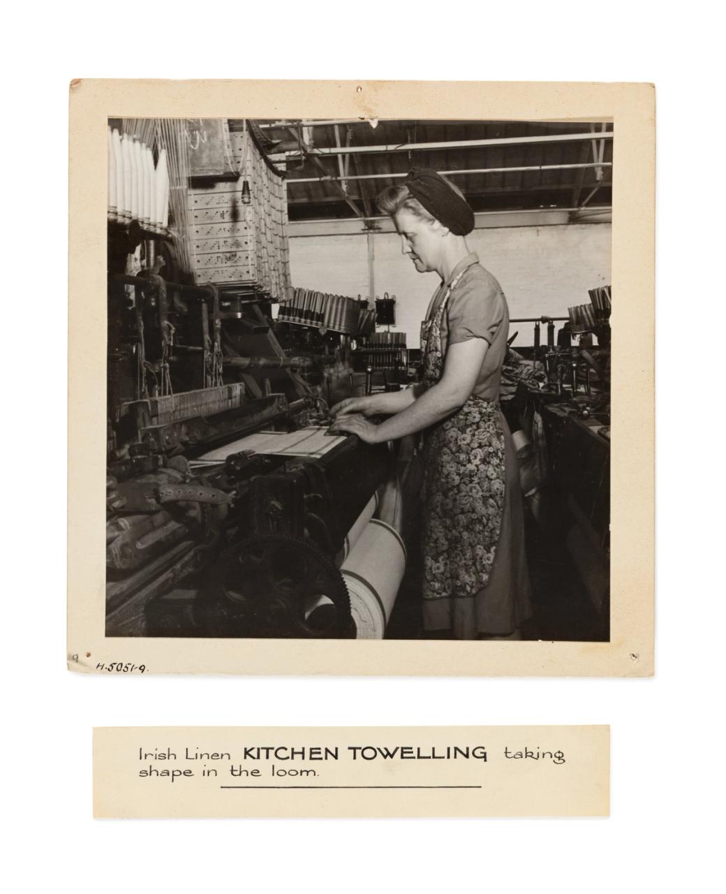 A photograph depicting 'Irish Linen kitchen towelling taking shape in the loom'. There is an associated and detatched label.