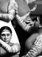 Image of seven First Nations dancers from Brolga Dance Academy posing against an ocean backdrop