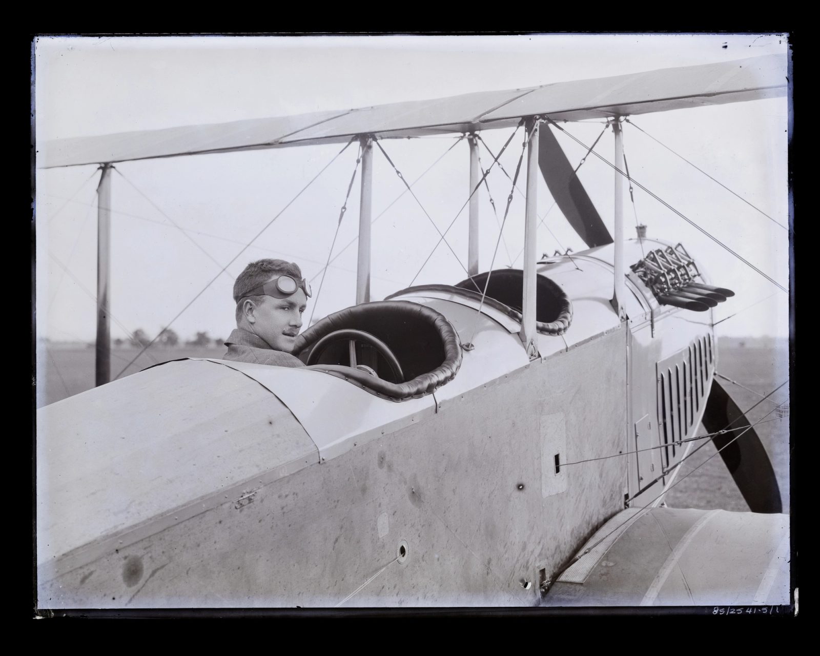 Glass plate negative, image of trainee aviator, probably Cecil Roy Burton looking left, wearing goggles, in on the NSW State Aviation School's Curtiss JN/3-4 aircraft at Richmond.
