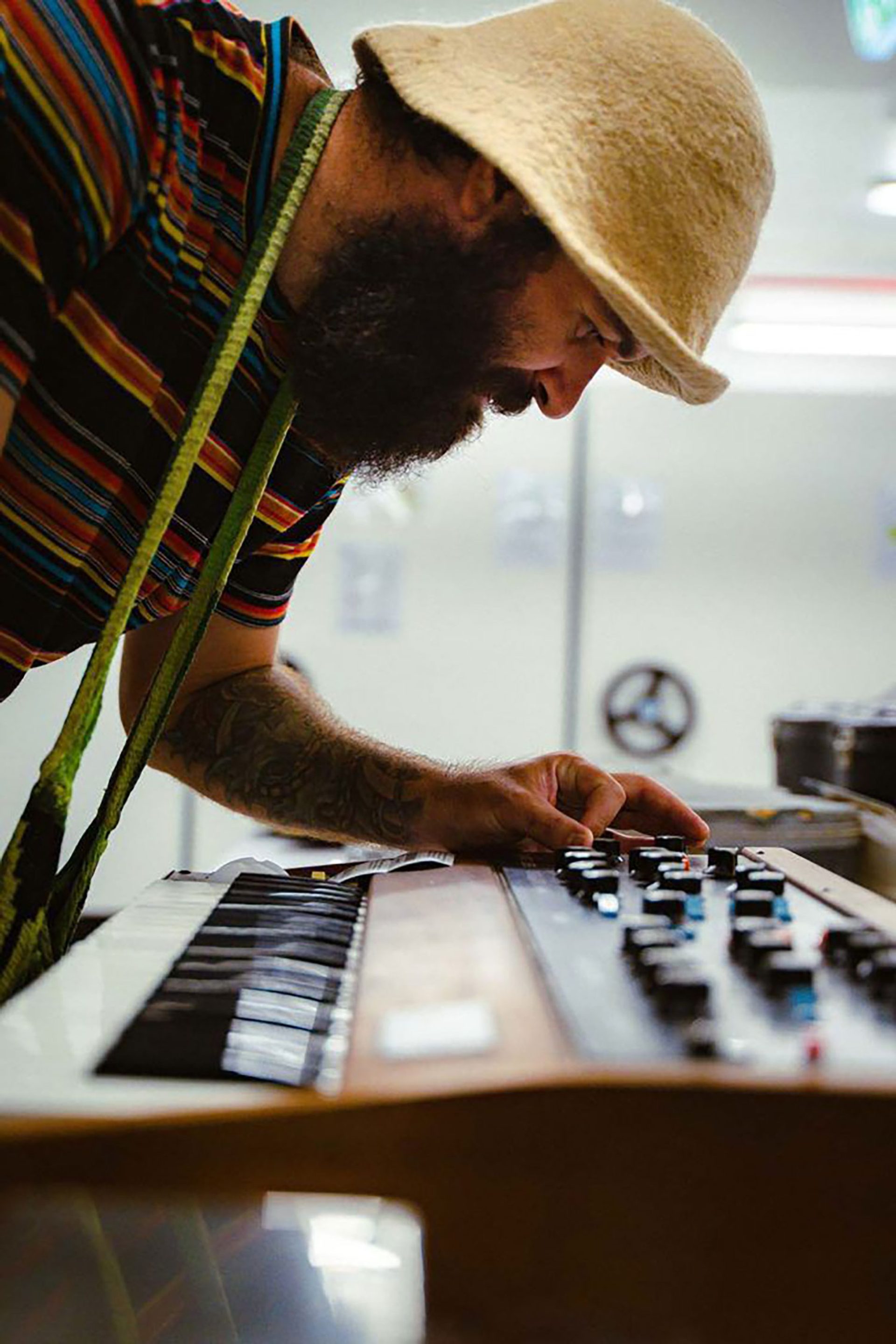 Joseph Douglas leans over a keyboard, twisting an effects knob.
