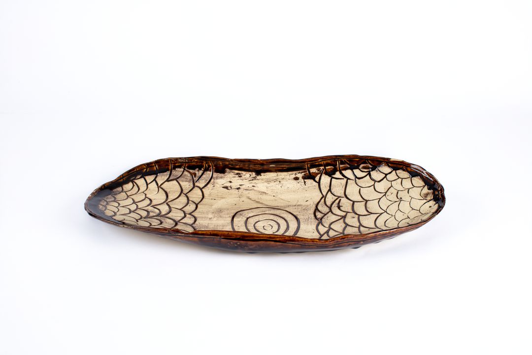 Hand formed ceramic platter shaped like a coolamon.