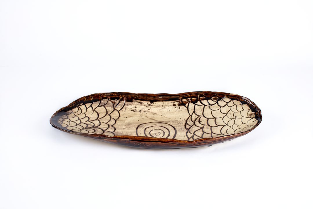 Hand formed ceramic platter shaped like a coolamon.