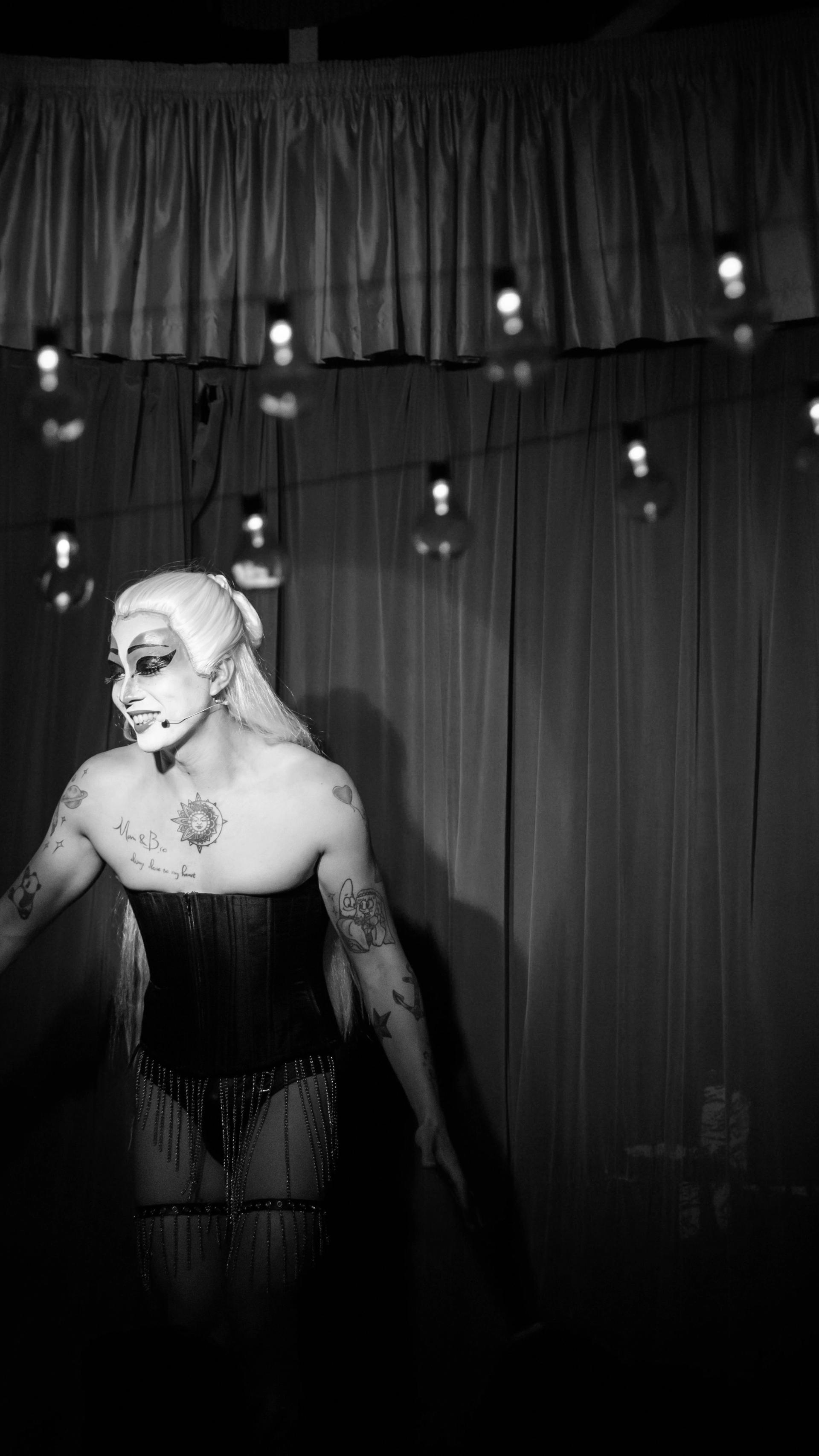 Figure in front of red stage curtains