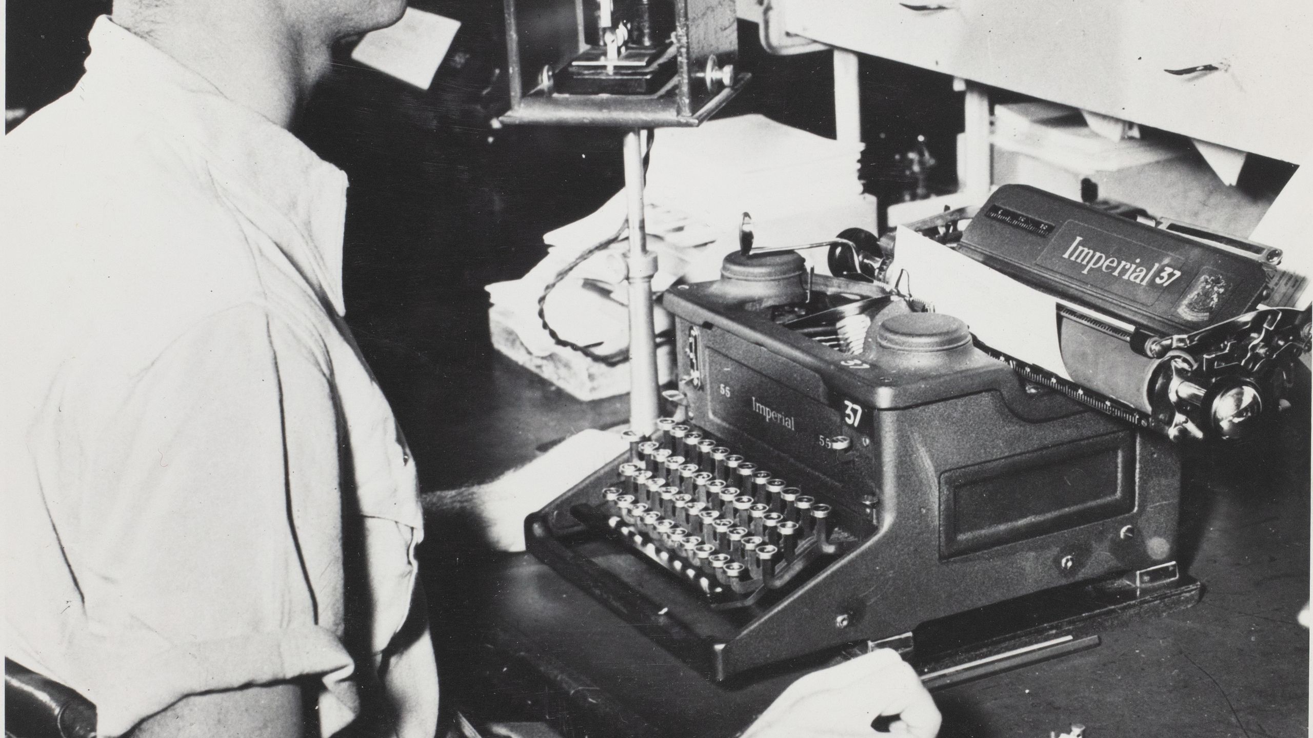 Black and white photograph of a morse code operator, a gentleman at a desk with morse code equipment.
