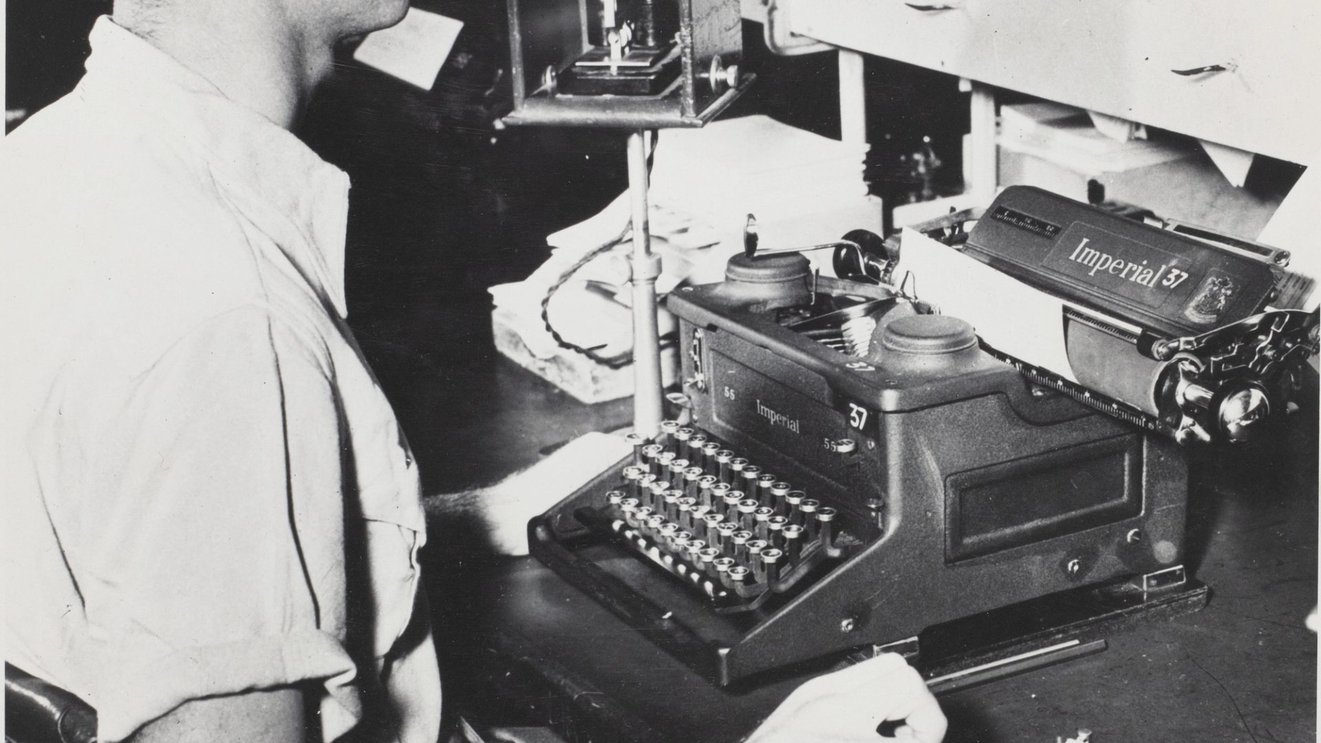 Black and white photograph of a morse code operator, a gentleman at a desk with morse code equipment.