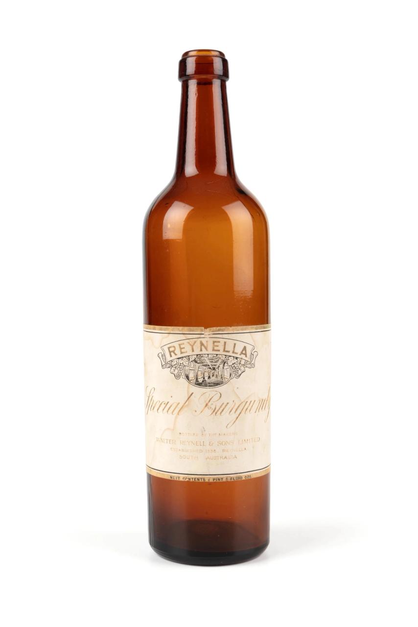 An amber glass wine bottle with a stained white label and a gold and black border.