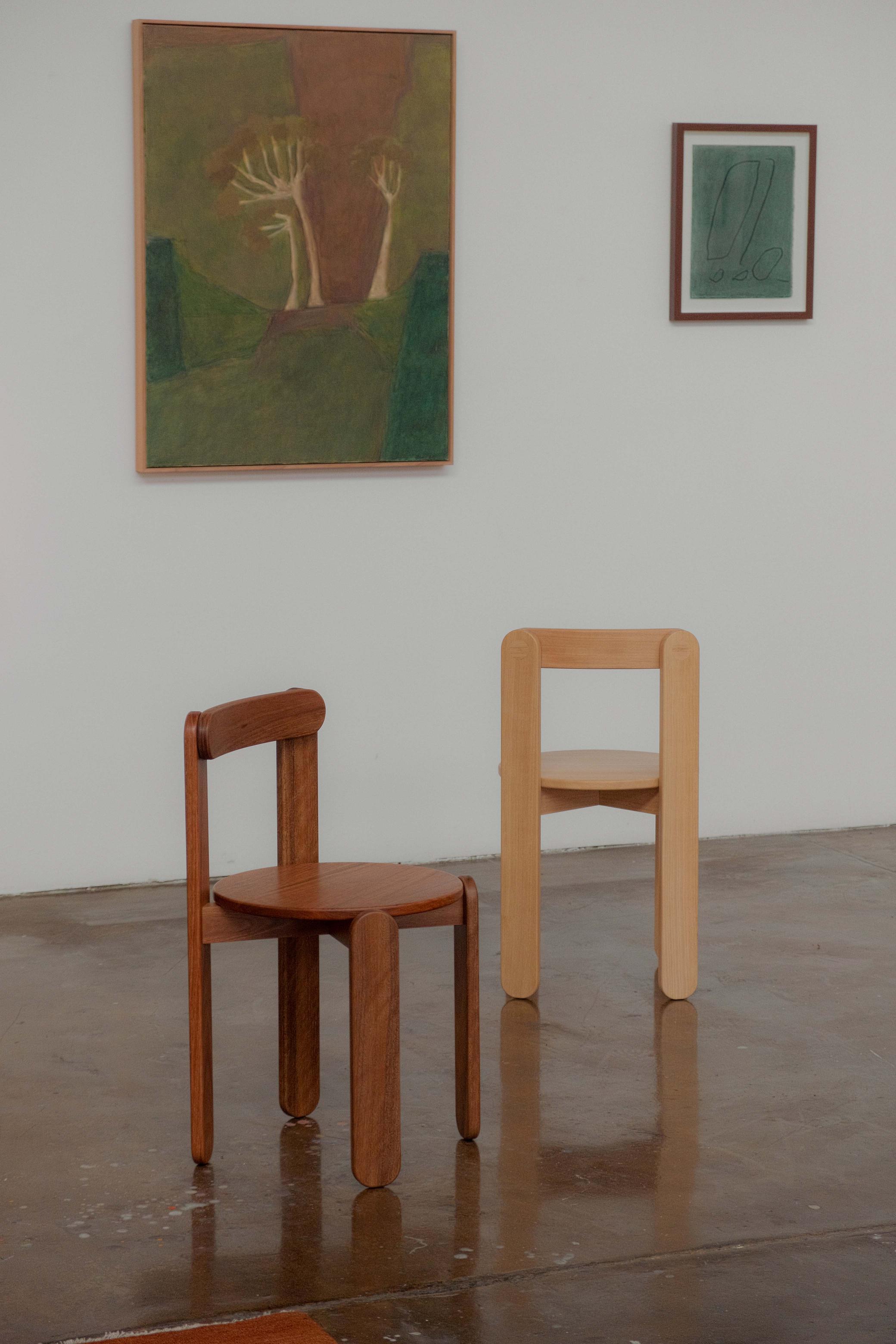 Two chairs sit in a gallery facing different directions.