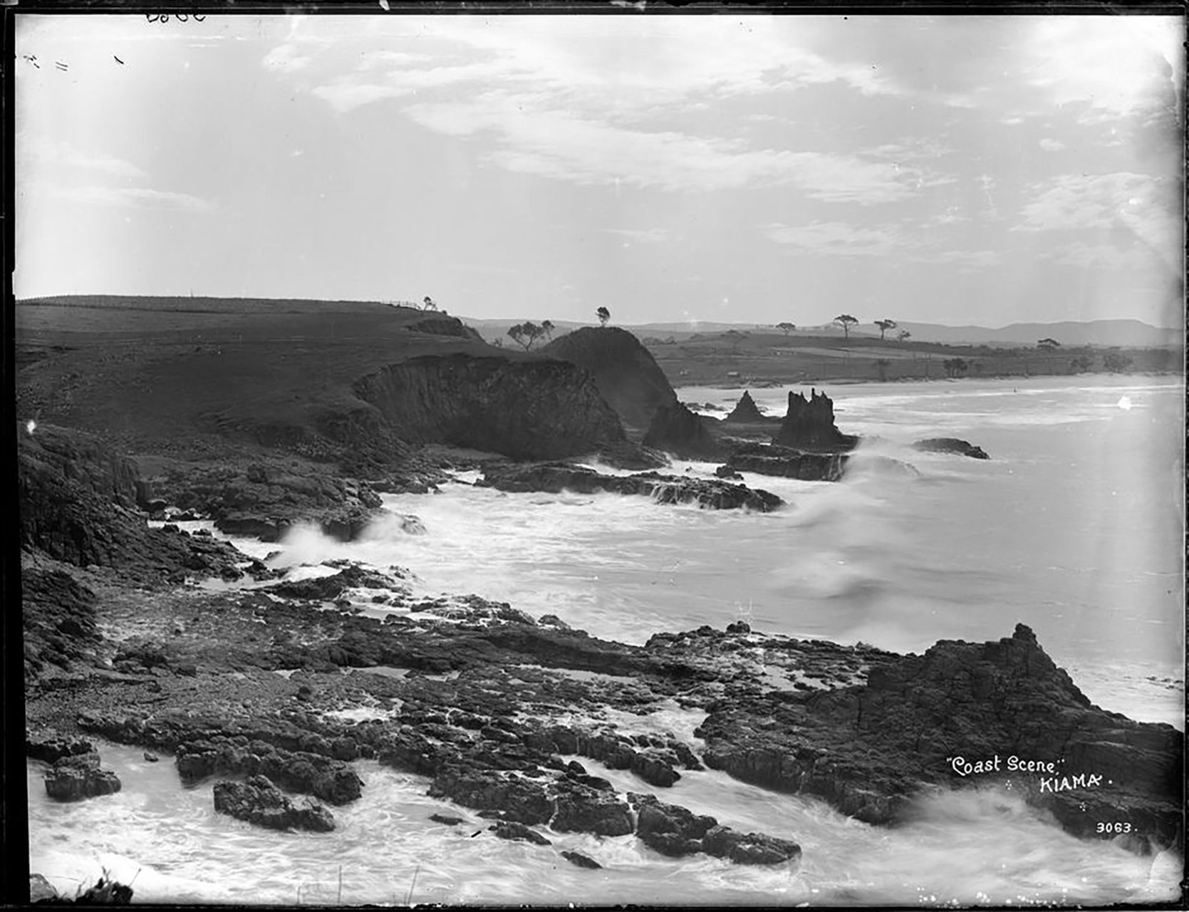 Silver gelatin dry plate glass negative in landscape format of the Kiama coast line. The caption and studio number are inscribed on the reverse of the negative.