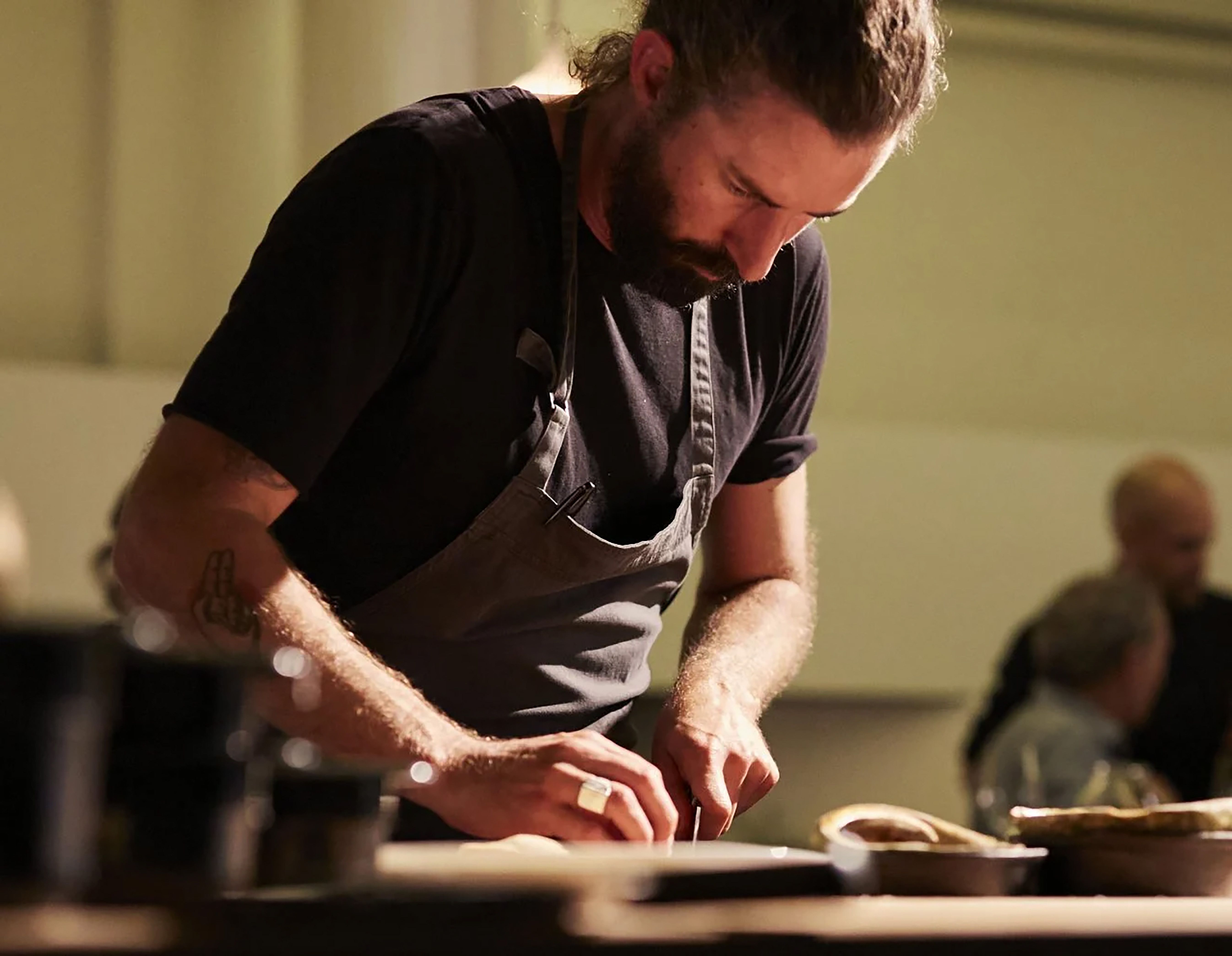 Chef in black and an apron, chopping.