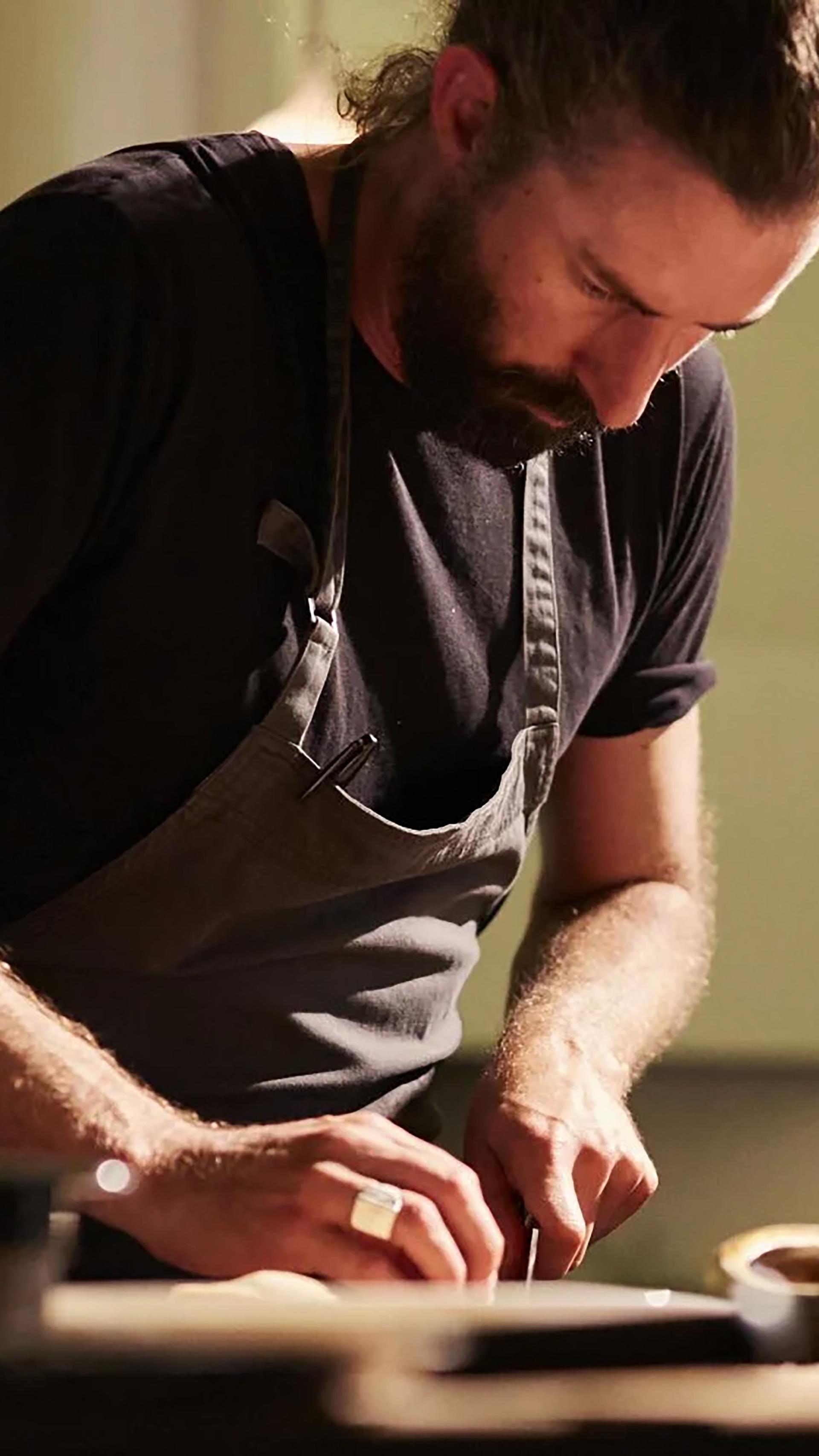 Chef in black and an apron, chopping.