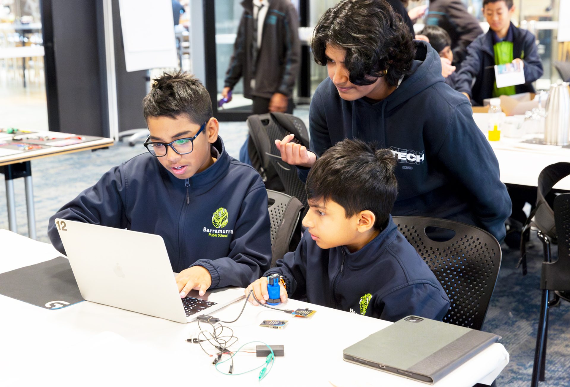 Three students working around a laptop.