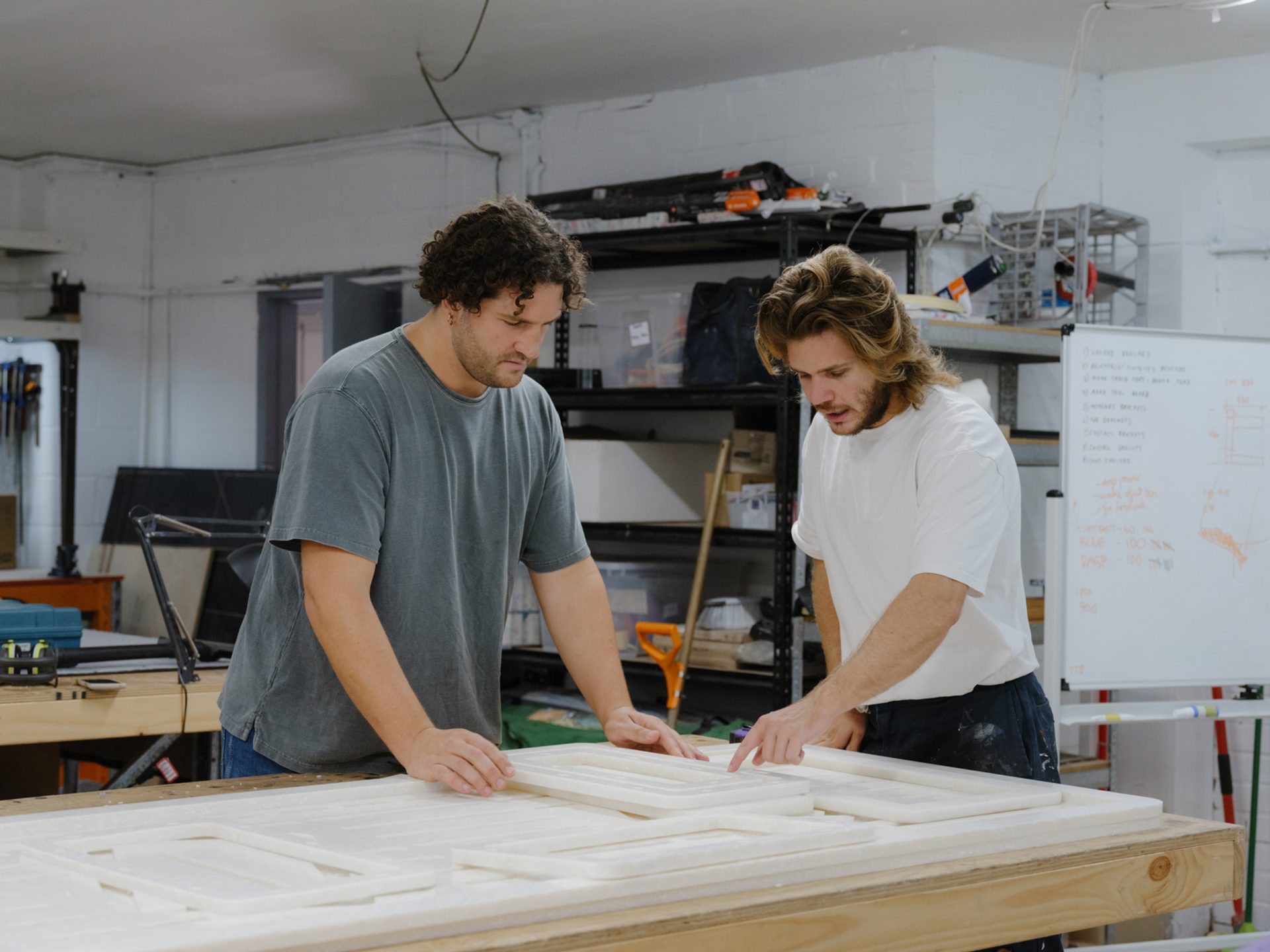 Two figures work atop a workbench.