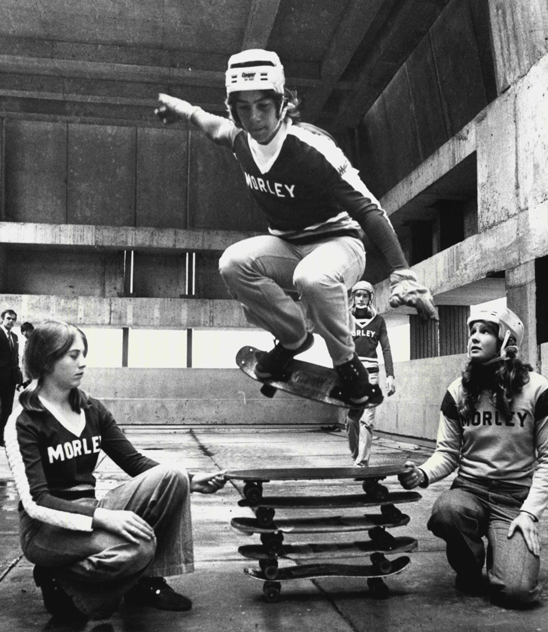 A black and white photograph of a man riding a skateboard mid-air.