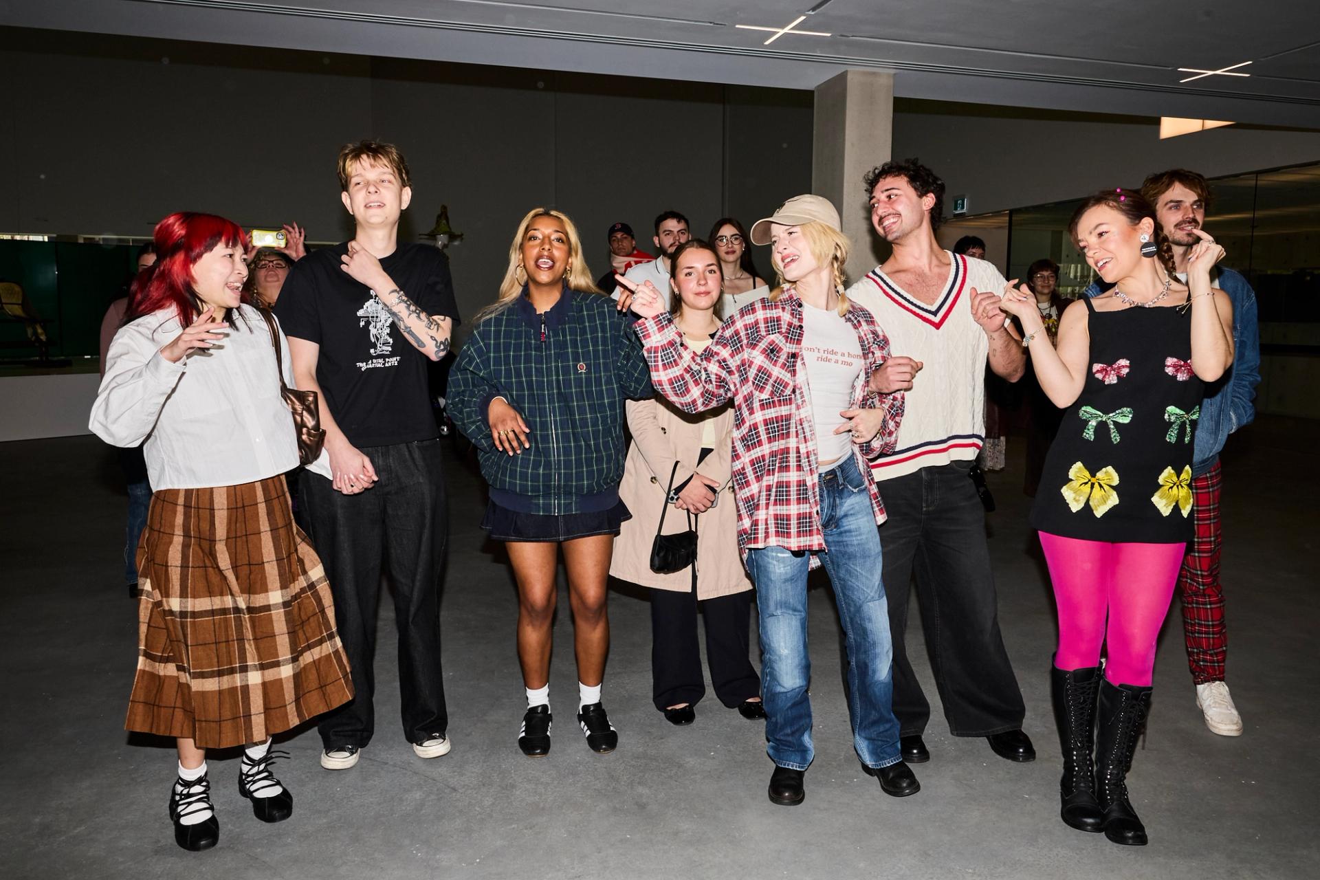 Guests Chloe Hayden and friends dancing and singing in a hall.
