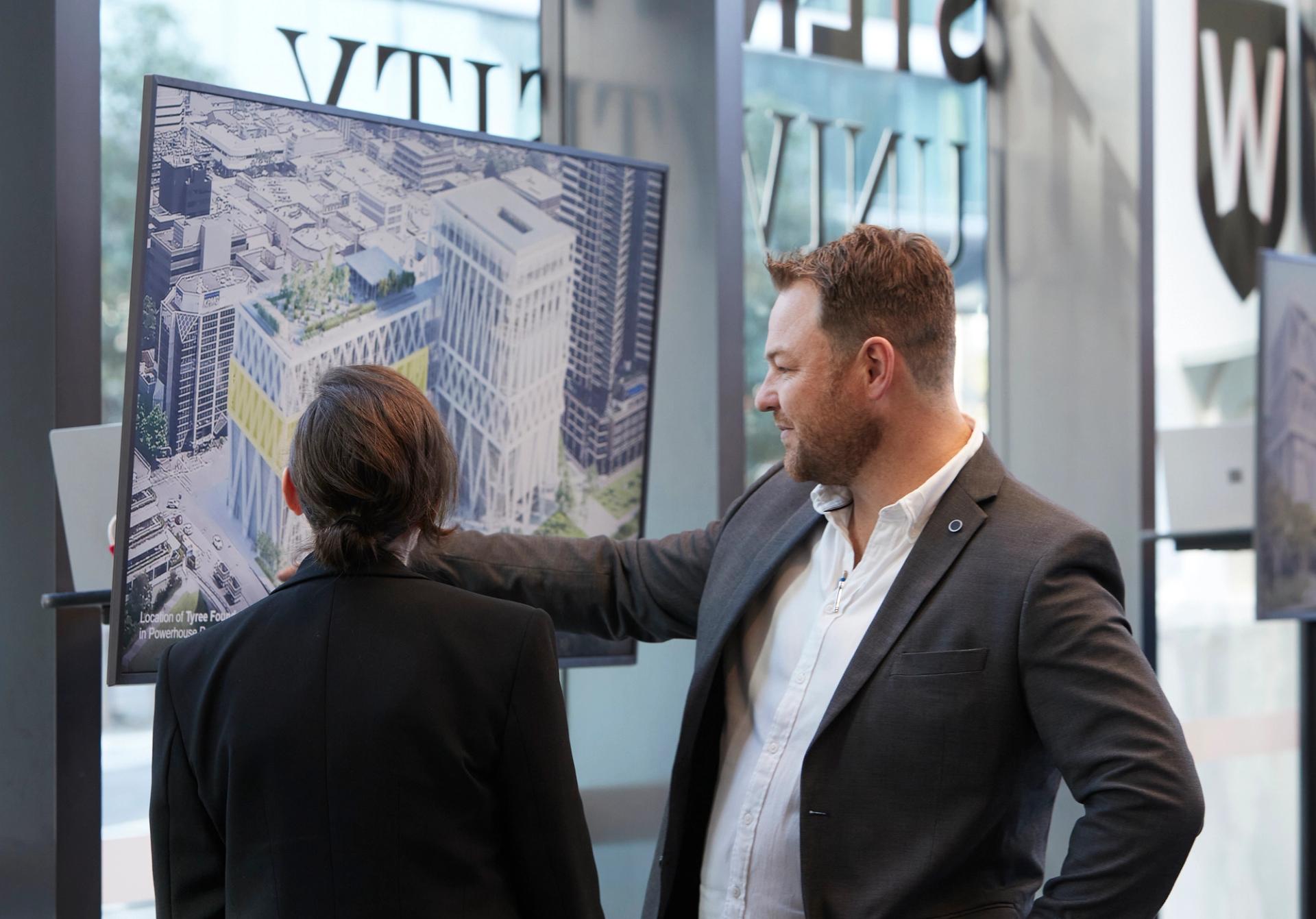 Two people looking at a screen with a building on it