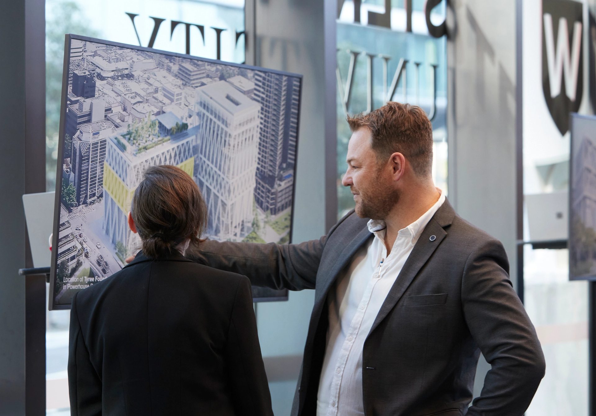 Two people looking at a screen with a building on it