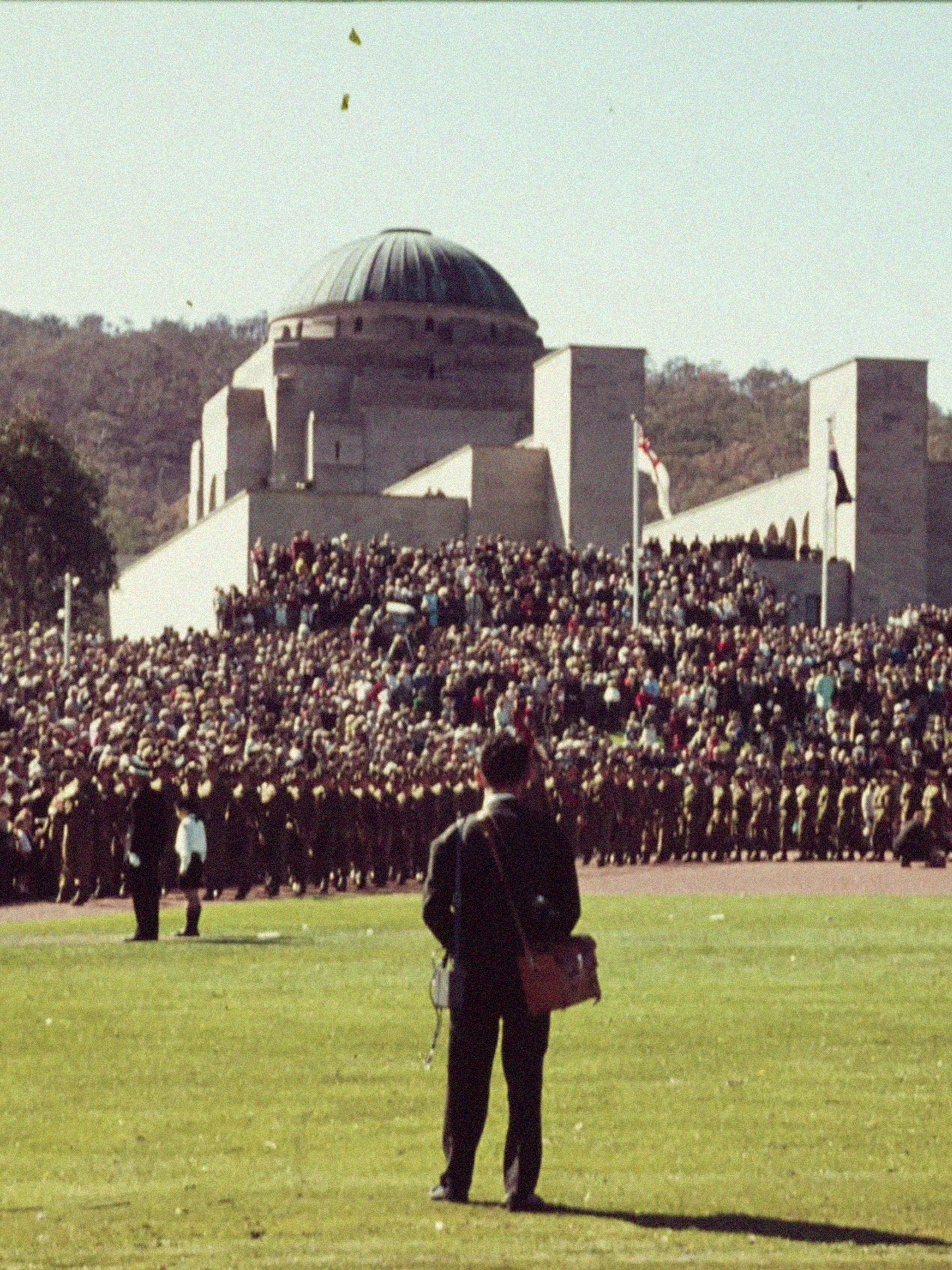 Man standing in field surrounded by those in uniforms.