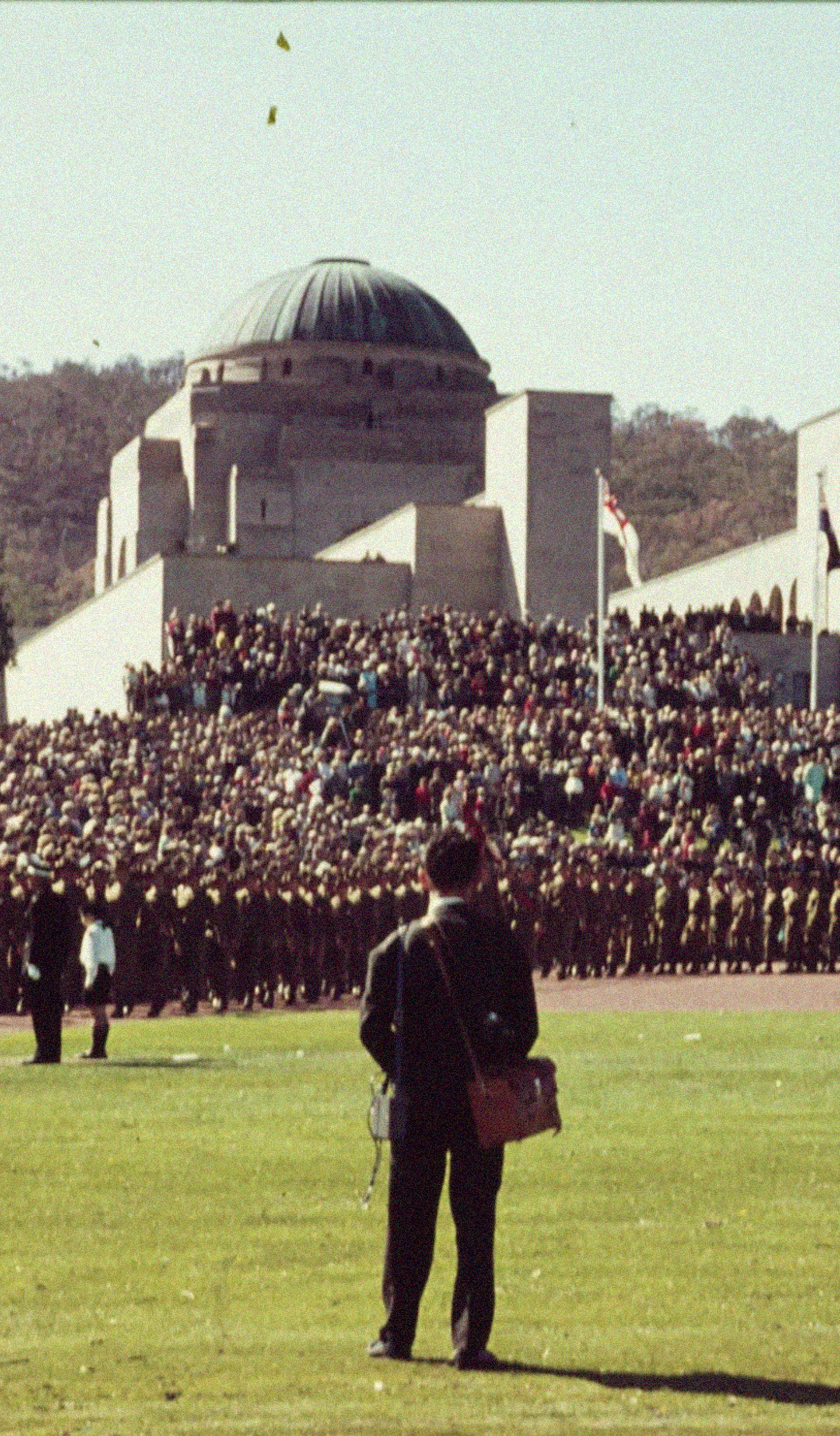 Man standing in field surrounded by those in uniforms.