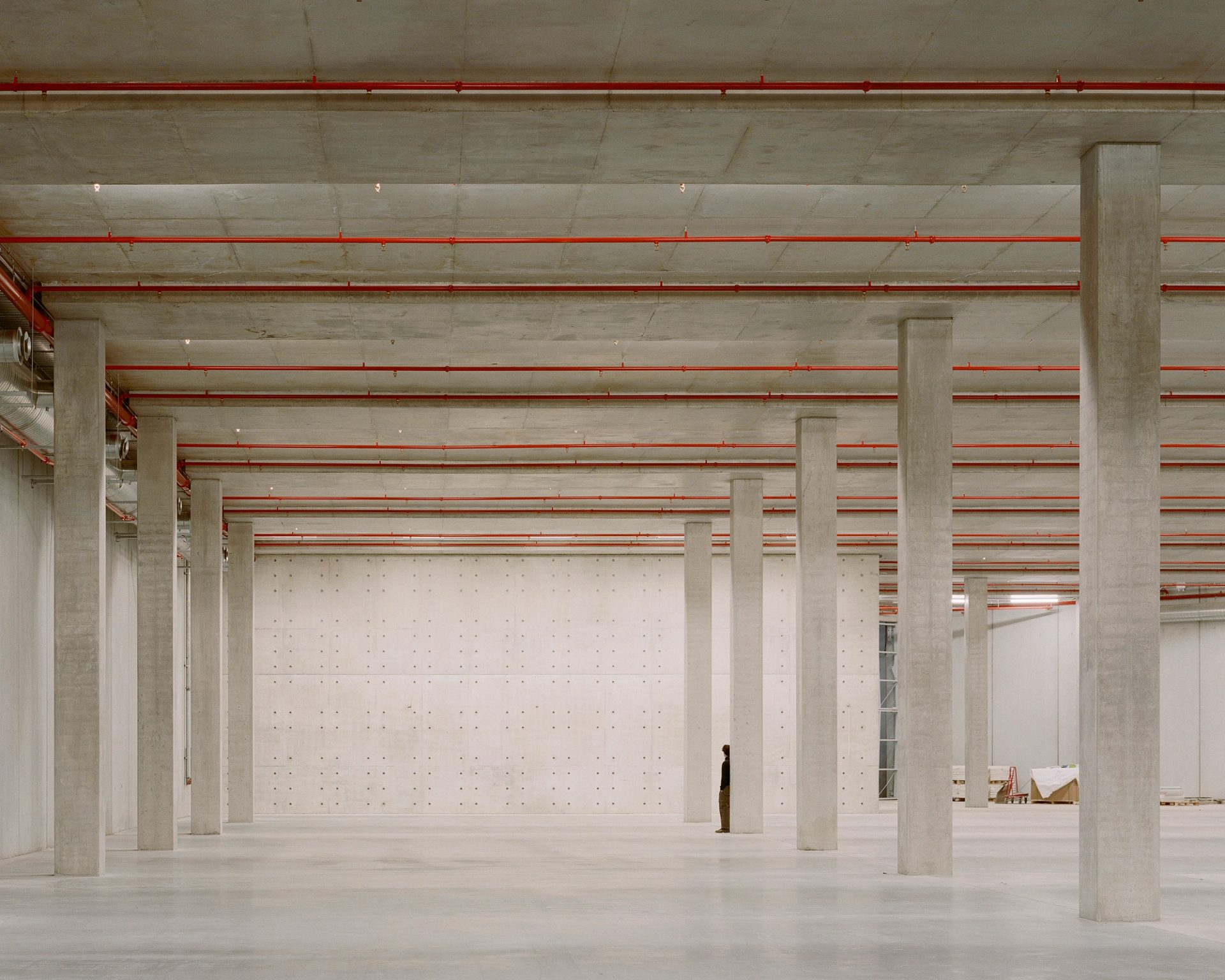 Concrete pillars inside an empty exhibition space, with a person for scale