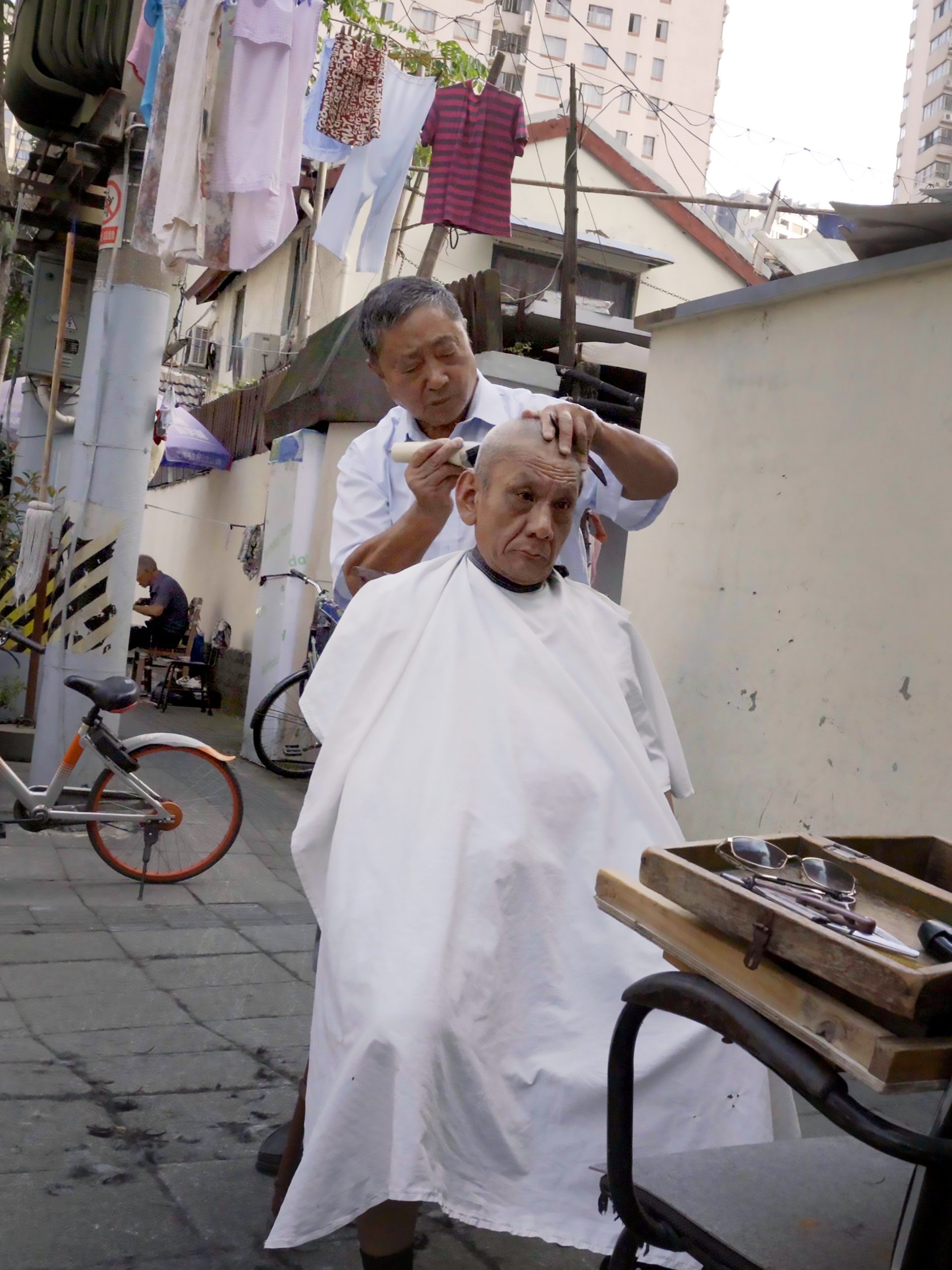 Two men in an urban streetscape having a haircut