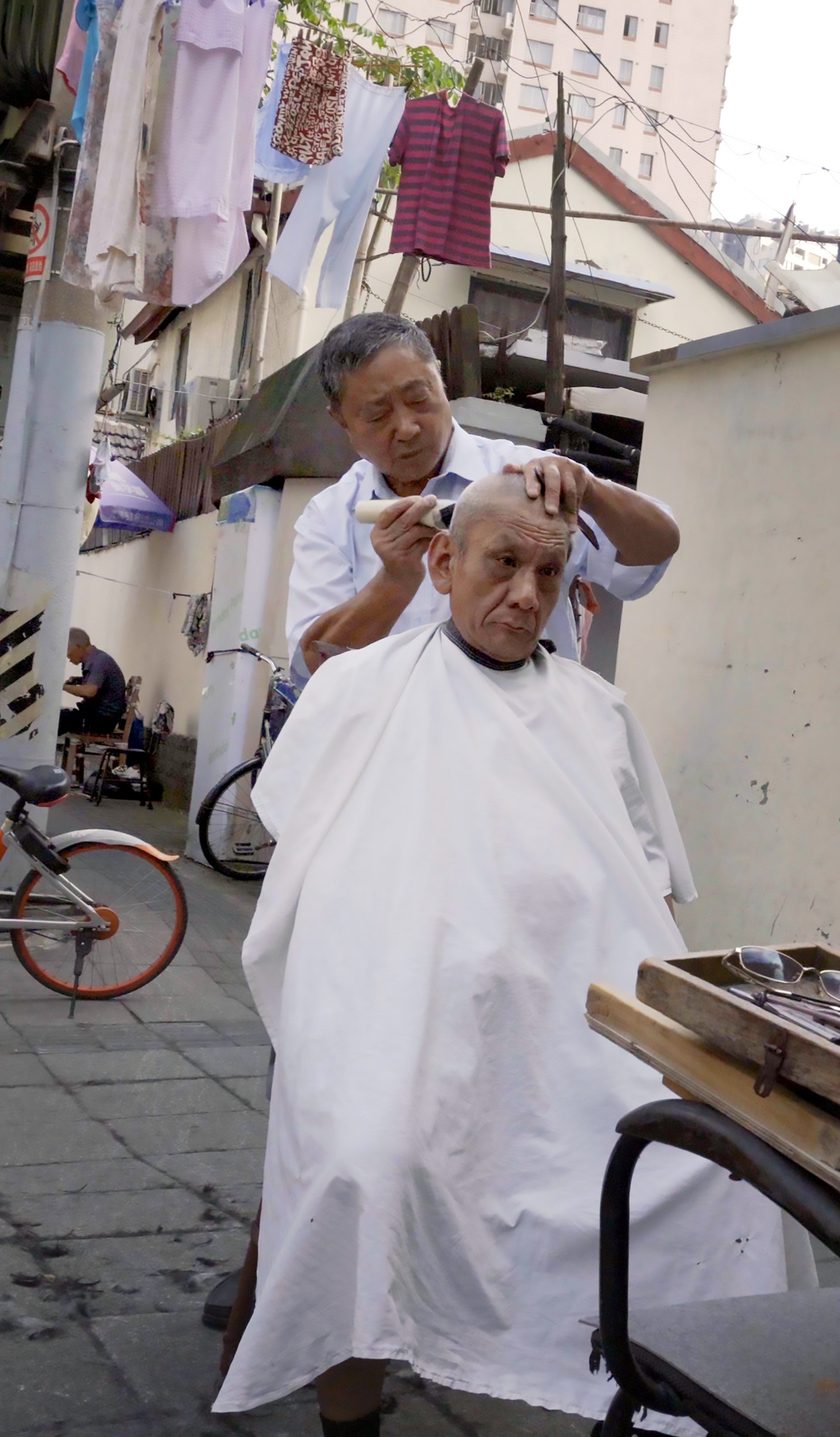 Two men in an urban streetscape having a haircut