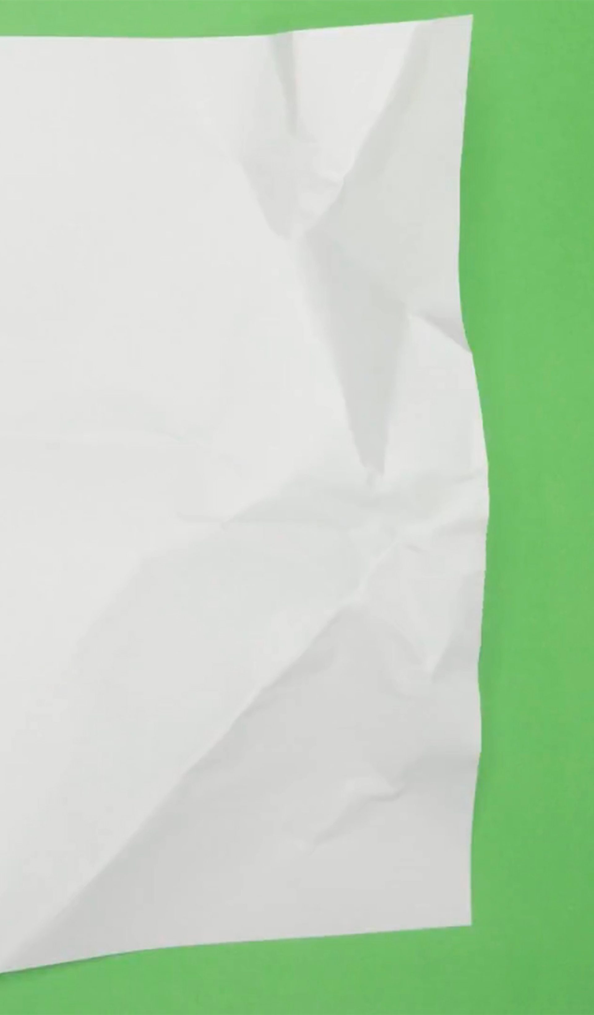 Animated footage of a sheet of paper being scrunched down to a ball, against a bright green background.