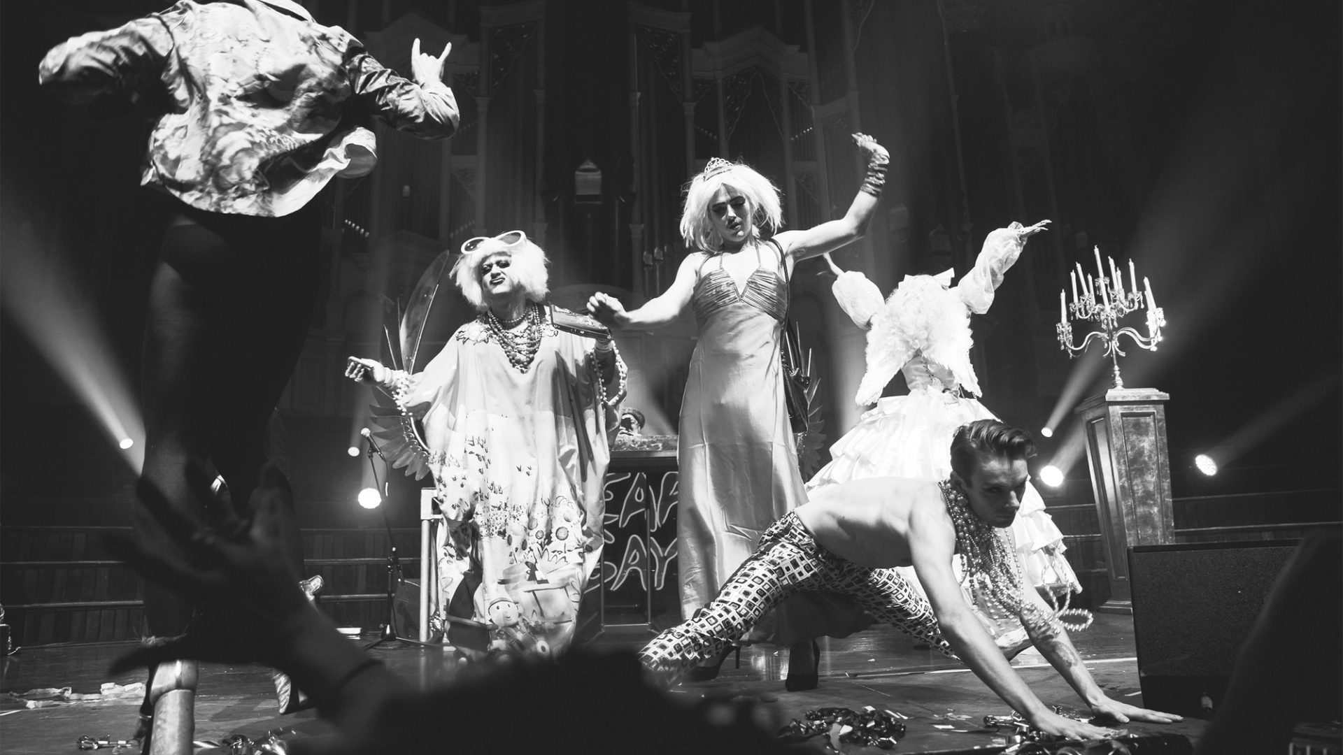 Black and white photo of five performers dancing on stage at a Heaps Gay party.