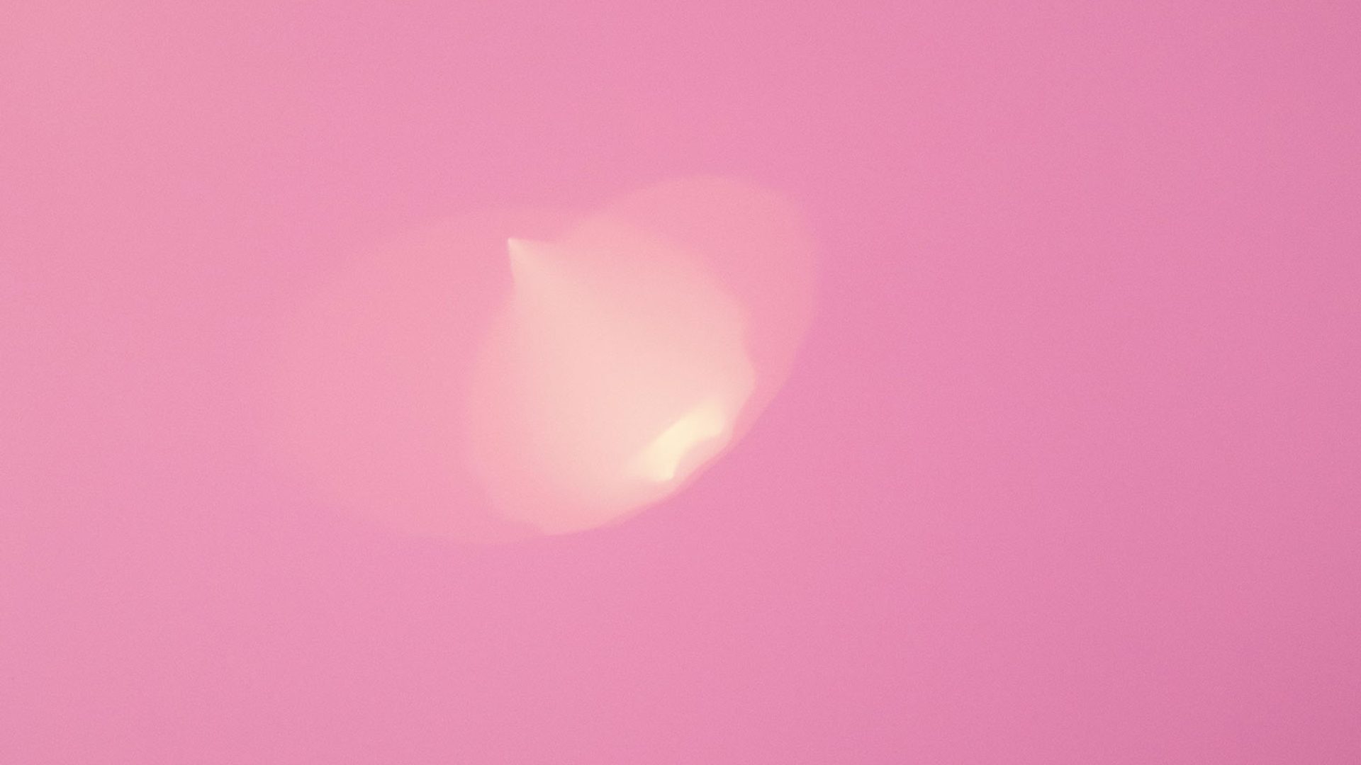 A dusty pink background with a small pale yellow light flare slightly off-centre