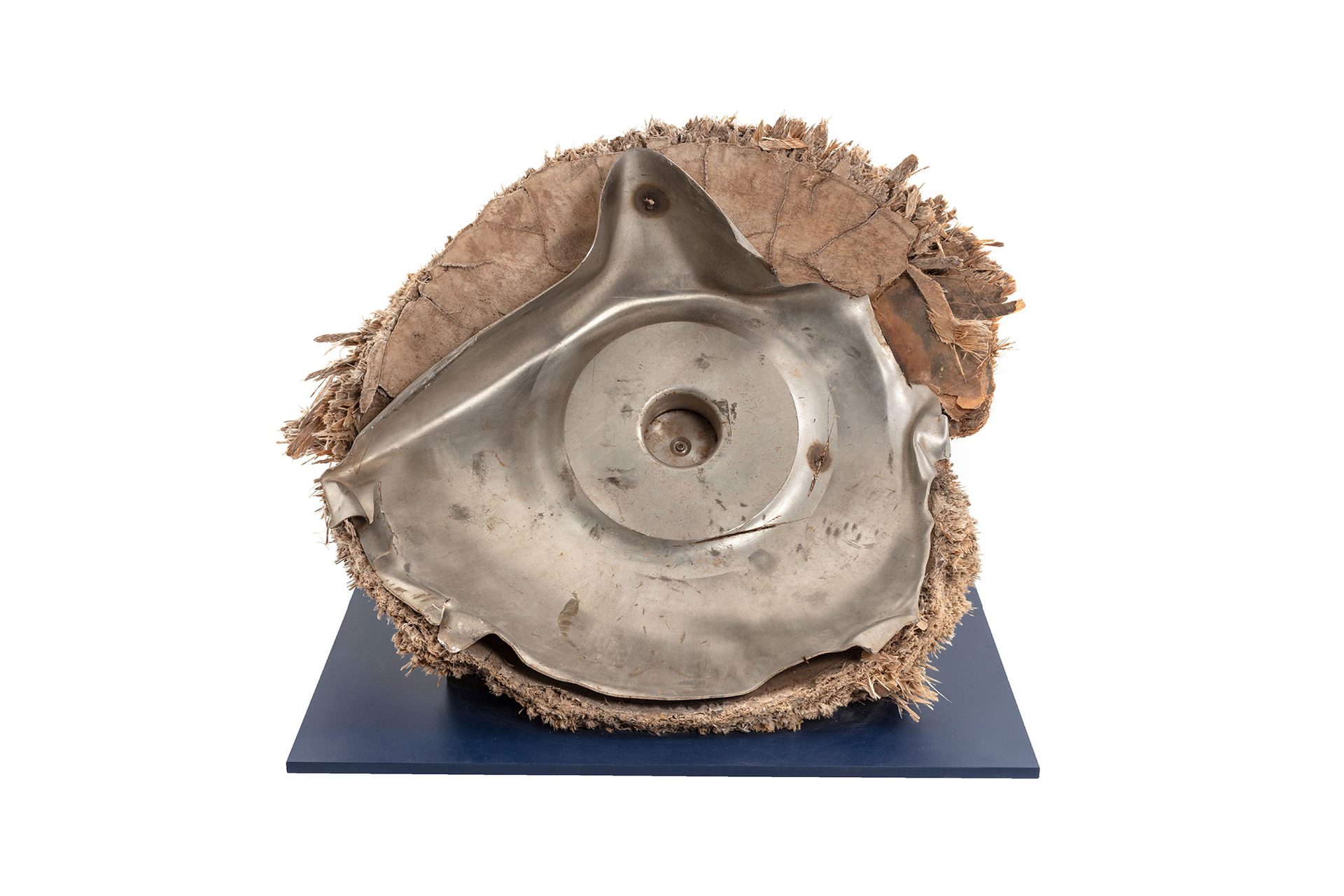 Space debris, Skylab space station, titanium/fibreglass, McDonnell Douglas Astronautics Co, USA, 1970-1972. The fragment is the end cap from pressurised oxygen tank from the Skylab space station. Originally the end of an enclosed cylinder, the titanium tank structure is torn and bent as a result of the stresses that ripped it away from the rest of the vessel. The exterior is covered by a composite insulation material with a woven fibreglass outer surface. A circular lid, protruding above the external insulation, covers an access hatch to the tank. A black and red wire, possibly originally connected to an external power source or sensor, is attached to the lid.