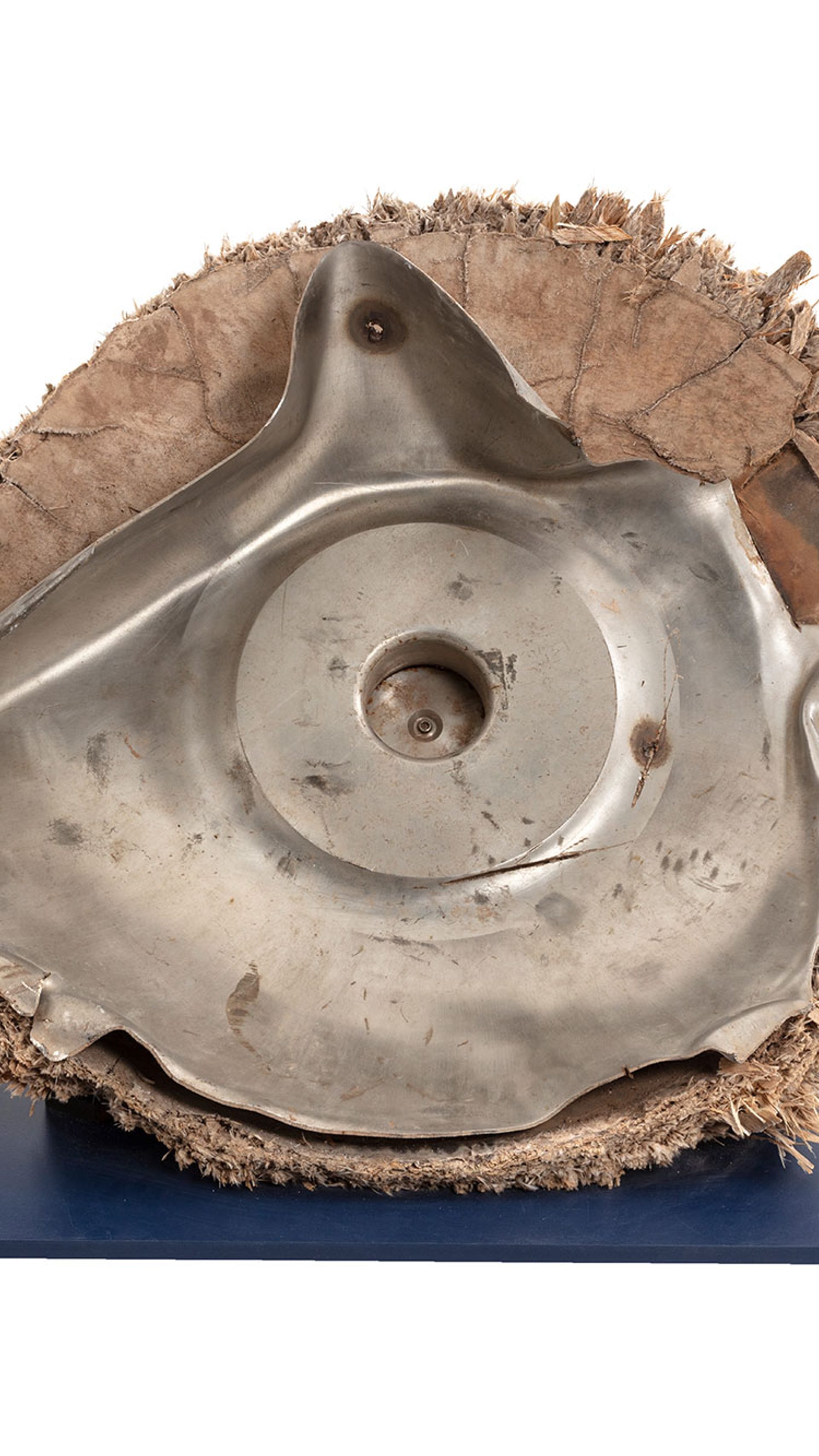 Space debris, Skylab space station, titanium/fibreglass, McDonnell Douglas Astronautics Co, USA, 1970-1972. The fragment is the end cap from pressurised oxygen tank from the Skylab space station. Originally the end of an enclosed cylinder, the titanium tank structure is torn and bent as a result of the stresses that ripped it away from the rest of the vessel. The exterior is covered by a composite insulation material with a woven fibreglass outer surface. A circular lid, protruding above the external insulation, covers an access hatch to the tank. A black and red wire, possibly originally connected to an external power source or sensor, is attached to the lid.