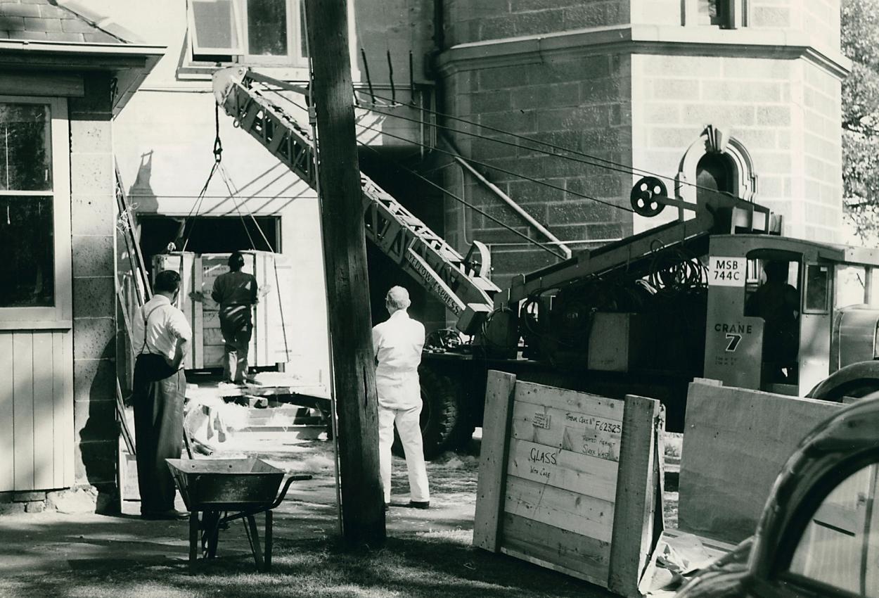 Black and white photograph of the machinery entering the observatory with a crane