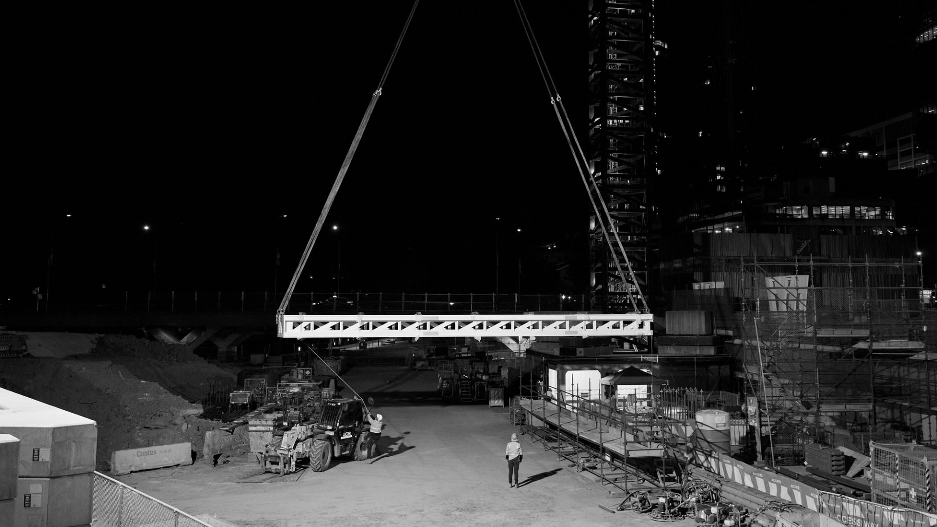 Construction site craning heavy frame at night
