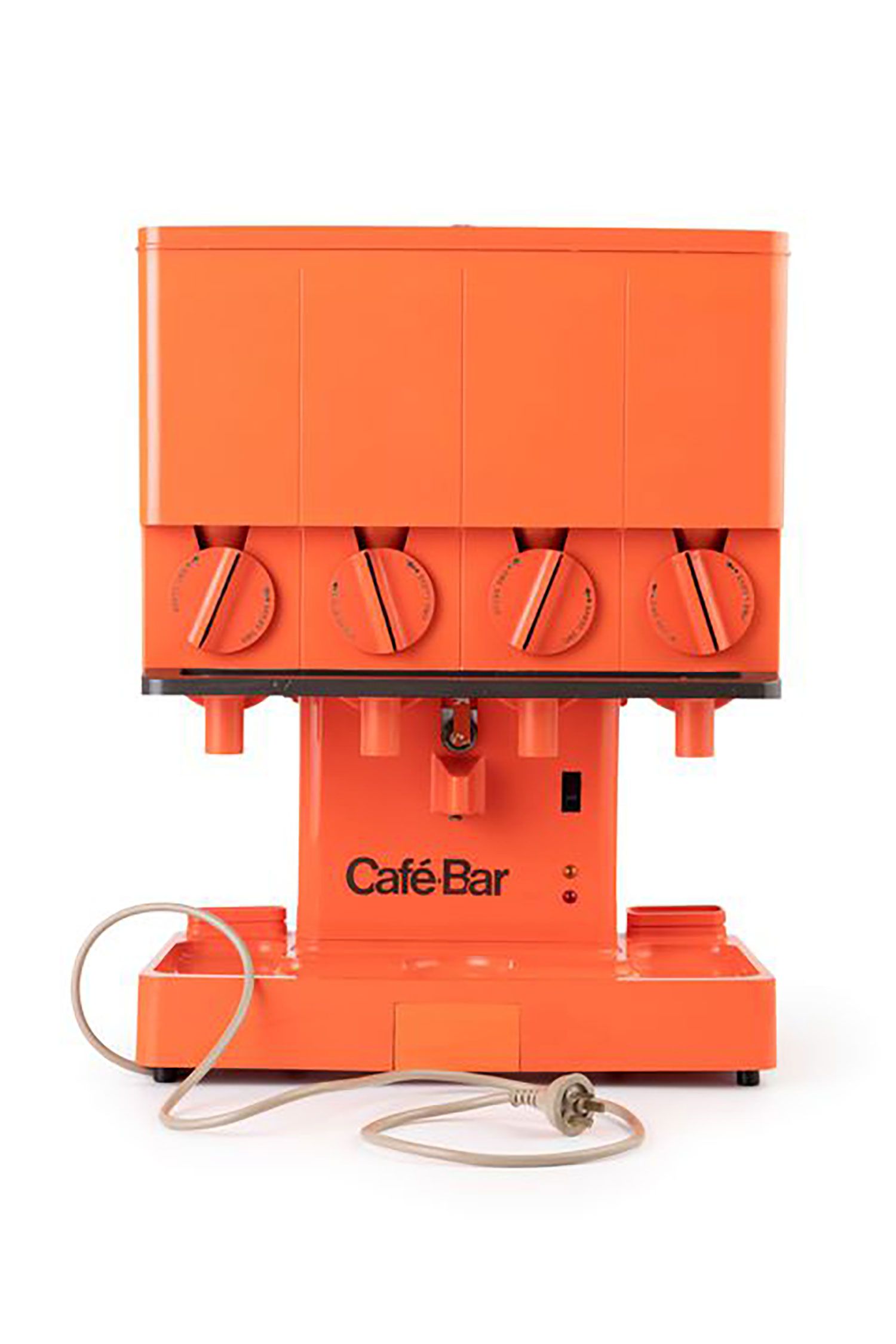 Hot drink dispensing machine constructed from orange moulded plastic. Formed with a box shaped dispenser suspended on a pedestal above a wide tray. The box shaped dispenser has a row of knobs across the front. The top of this module hinges open to reveal dispensing mechanism inside. A column of white plastic cups protrude from a hole in the back underside of the box.