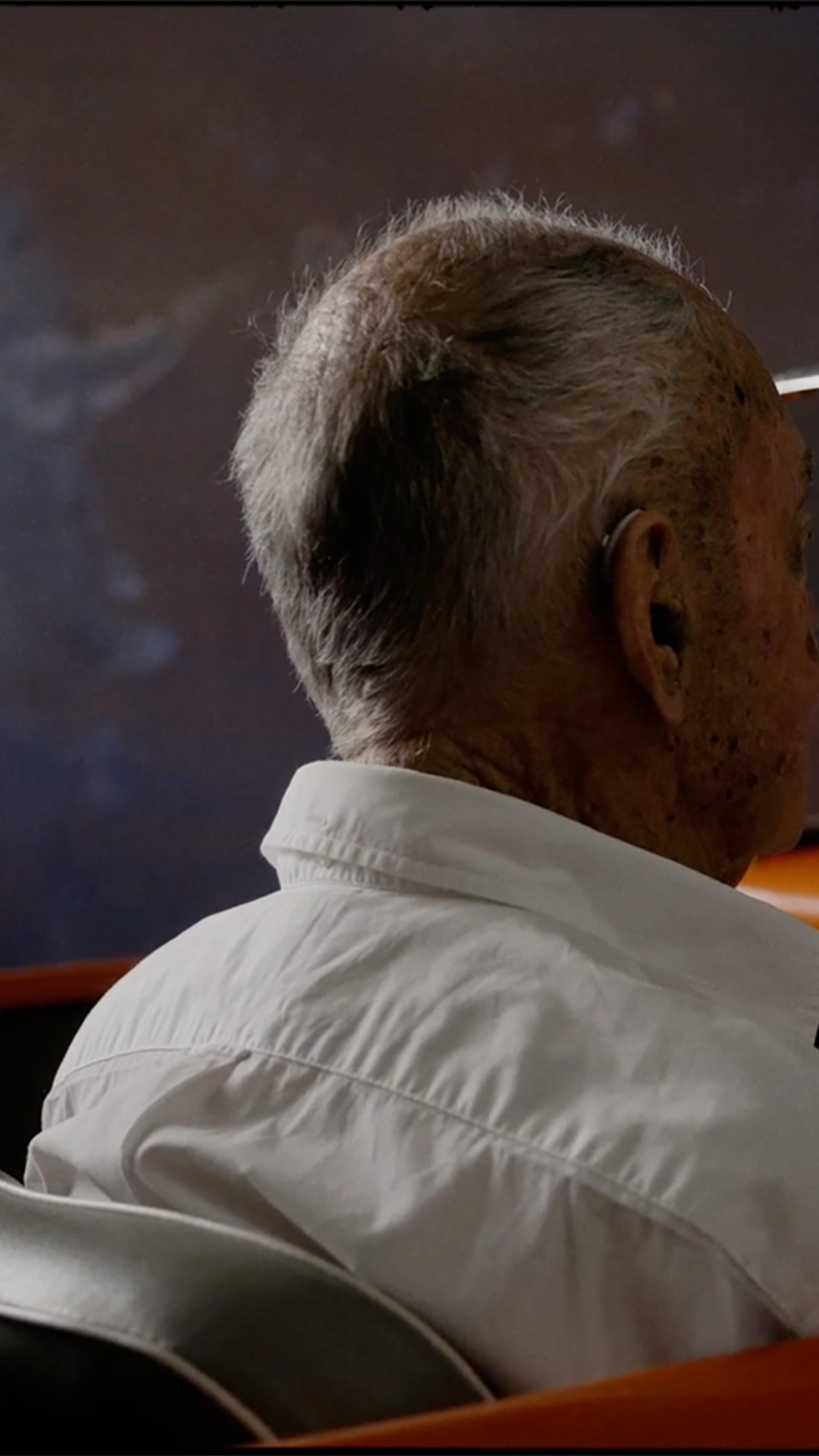 Figure sits behind the steering wheel of an orange open roof car