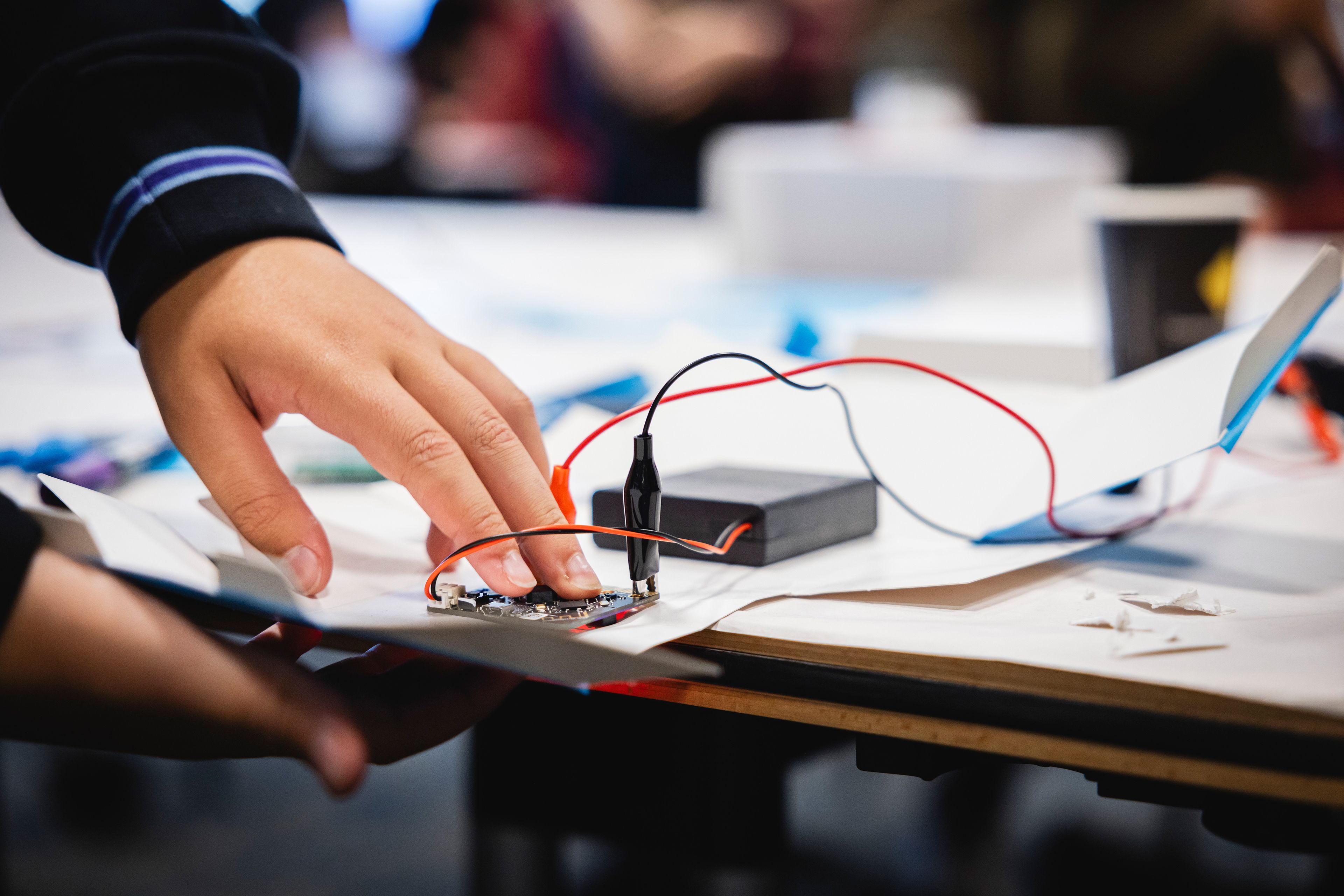 Close-up photo of a student working with cardboard and mechanical parts on a table.