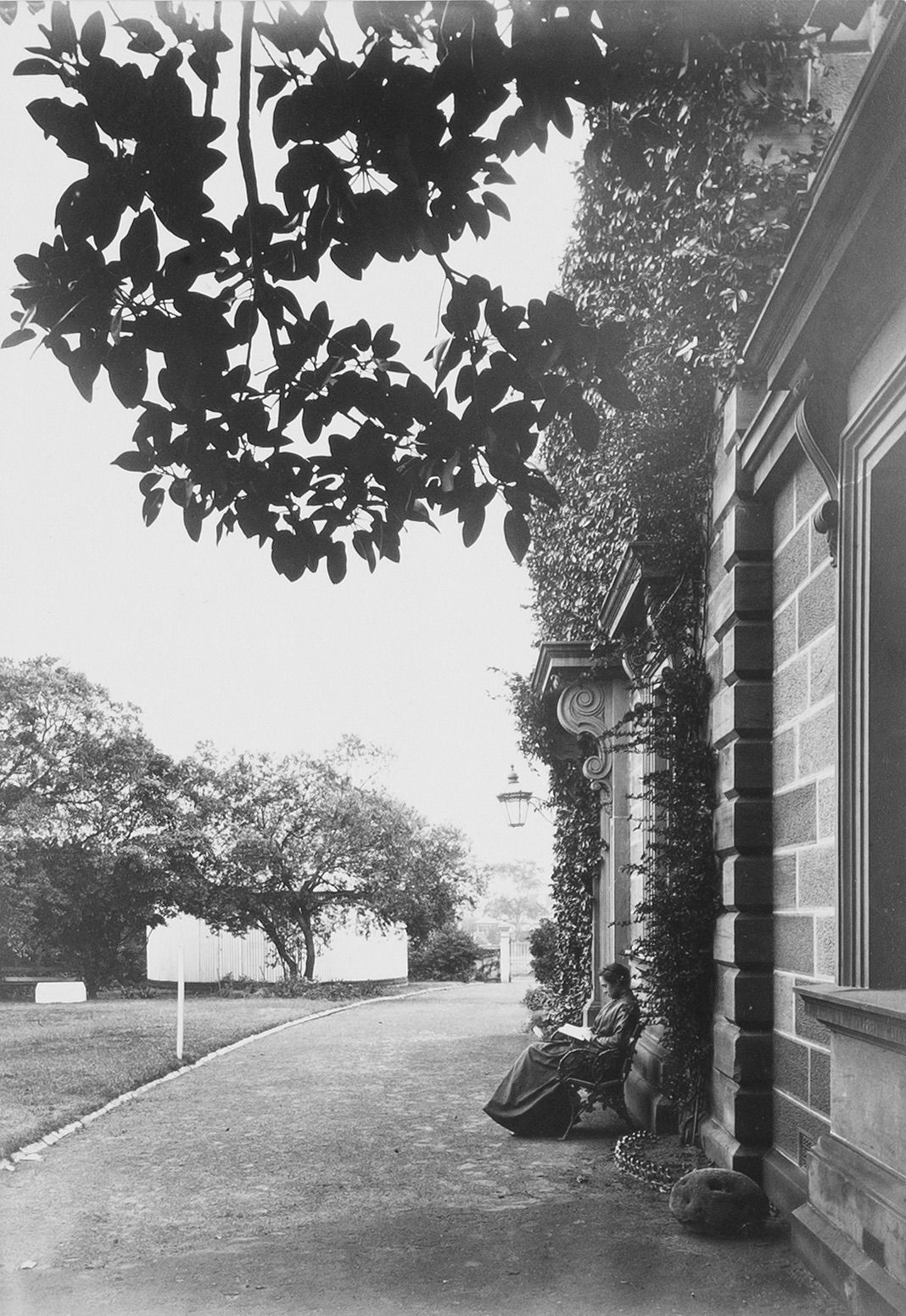 Woman sitting on a bench outside of an old building.